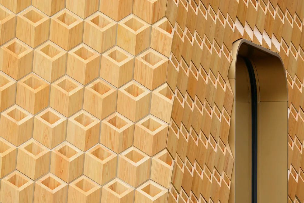 木質立面便是以日本扁柏(Hinoki)製作。日本建築使用日本扁柏的歷史悠久,不少古代建築像是神社、寺廟都採用這種材料,其穩定性高、耐候,且有著讓人感覺溫暖的色調。KDa 選用 60~70 年樹齡的日本扁柏,由京都木匠師傅以傳統細木工技術手工製作,打造出 12 種不同形狀,共 2,500 多個幾何單元,再將這些單元連接到以回收鋁製成的結構框架上,才完成了這個精巧細緻的立面