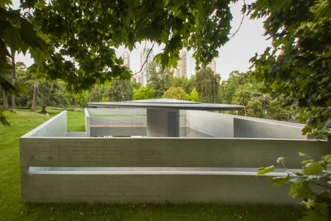「MPavilion 10」建築主體為一直徑14.4公尺的圓形屋頂,底部以圓柱支撐,四周由兩組錯開的ㄇ字型外牆圈出一方形場域,宛如靜謐的避世之所,也令人聯想起傳統日式花園的格局。此外,於兩面南北牆上各有一道平行的切口,縫合了展館內外的空間,而透過內部的半反射池,天地景緻與建築洗鍊的線條都將在此交匯,相映成趣