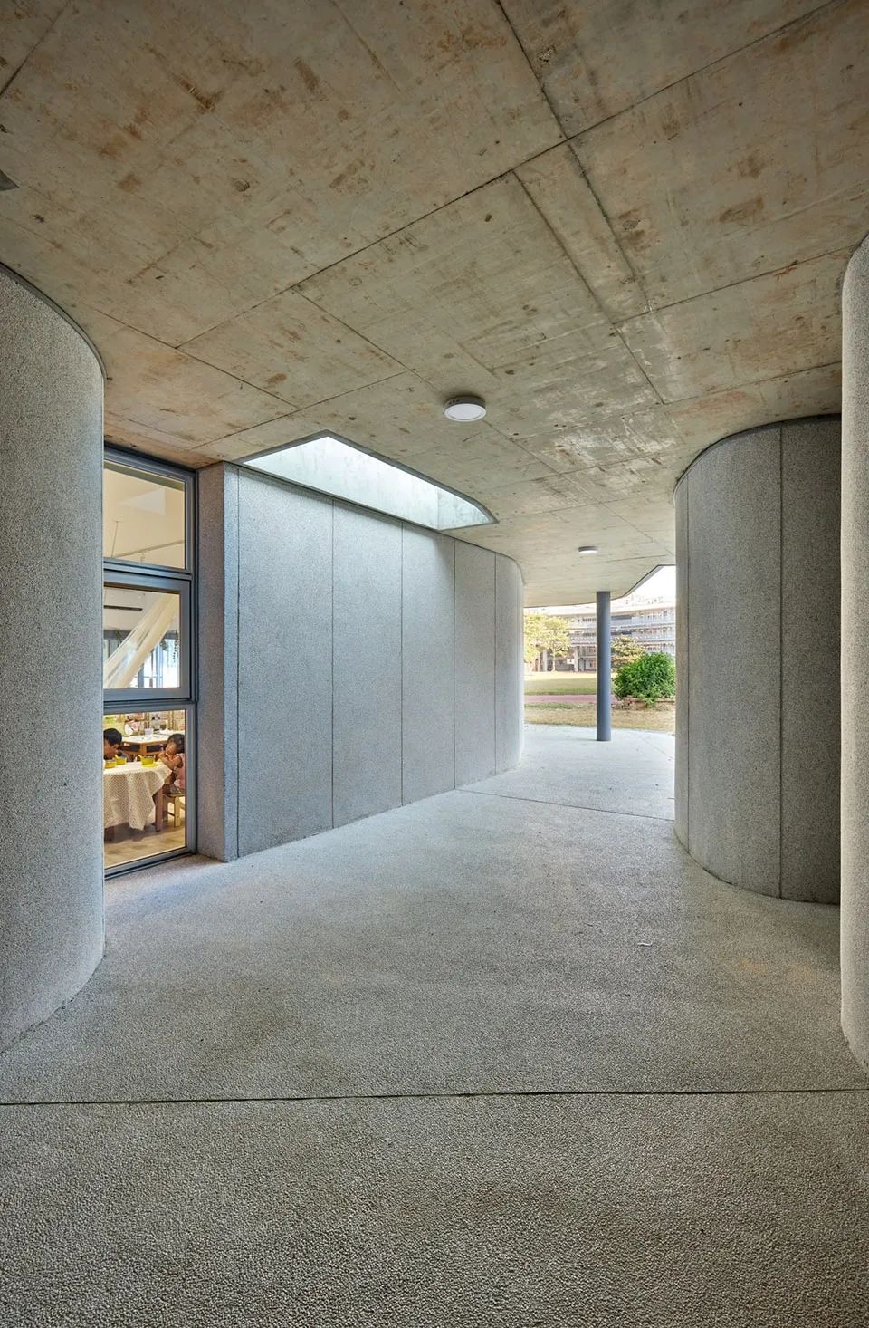 由地面層縫隙空間看室外，新竹市三民國小幼兒園／境衍設計 林柏陽建築師事務所