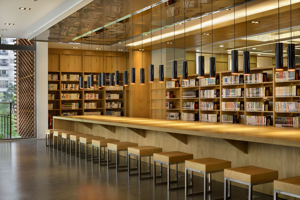 3F圖書館，開闊的長型閱覽桌與包覆出回字型書海的書櫃群