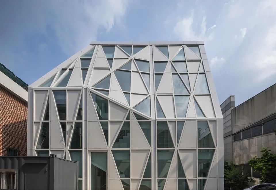 首爾面牧洞市場客服中心/UnSangDong Architects 韻生同建築師事務所 豐富的構圖與三角形帶來的動感使立面成為市場與繁忙日常生活中迸發出的活力的象徵,明亮且尺度宜人的建築立面也成為市場街道中一道靚麗的都市景觀