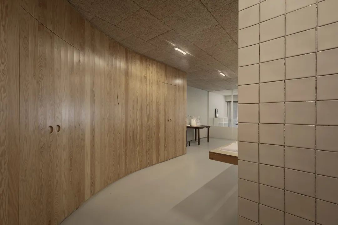 儲藏室與洗手間等服務空間隱藏在曲面木牆後 lisbon office interior design 里斯本辦公室室內設計D-A Studio／Domitianus-Arquitetura