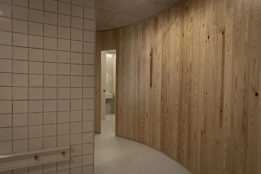 儲藏室與洗手間等服務空間隱藏在曲面木牆後 lisbon office interior design 里斯本辦公室室內設計D-A Studio／Domitianus-Arquitetura