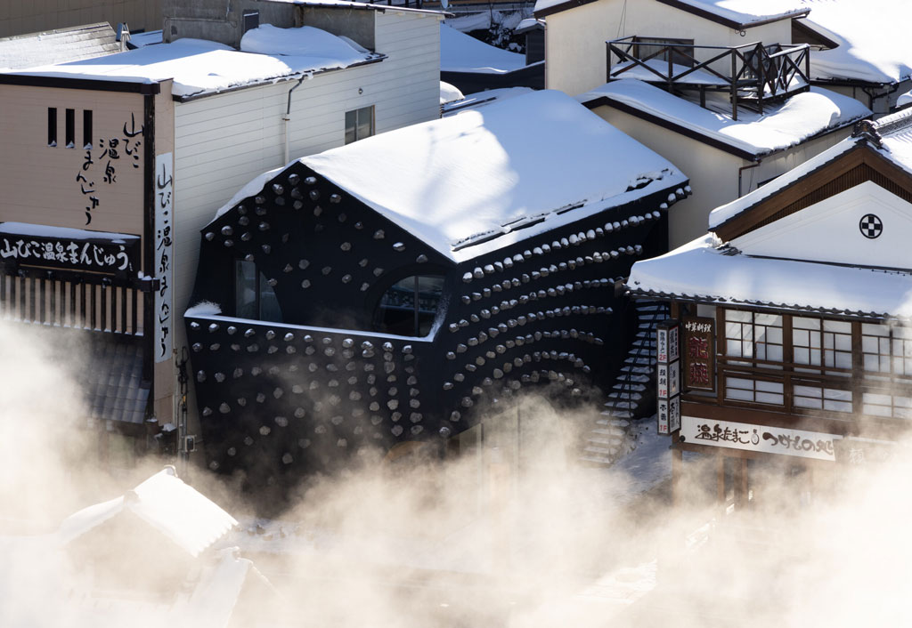 冬季時，草津温泉きむらや的黑色外觀屋頂上覆蓋著白雪，周遭被白色水氣環繞，宛若幻境