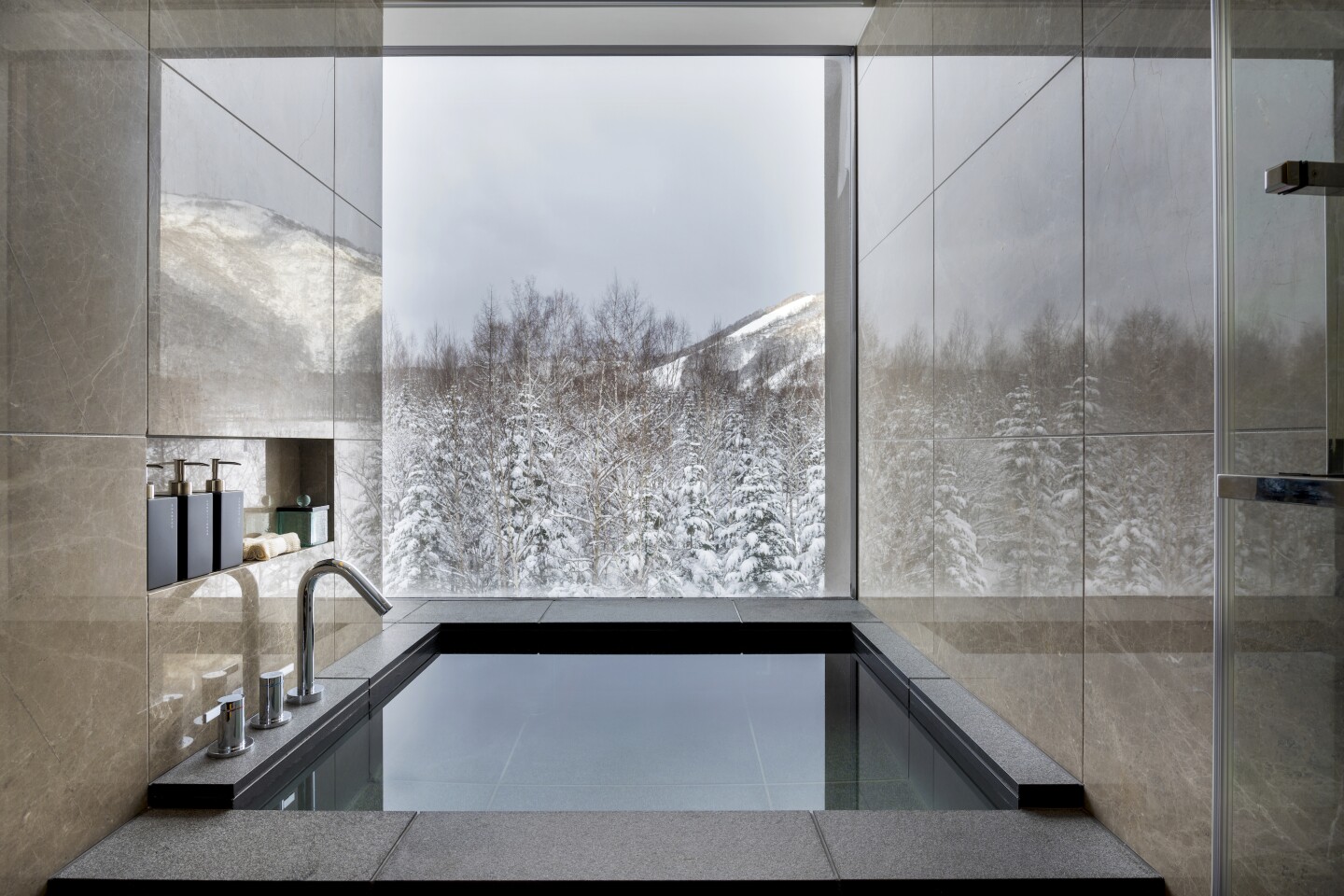 An ofuro bathtub in a suite at Higashiyama Niseko Village, a Ritz-Carlton Reserve.  客房內溫泉望見的雪景（東山二世古村-麗思卡爾頓隱世精品度假飯店）