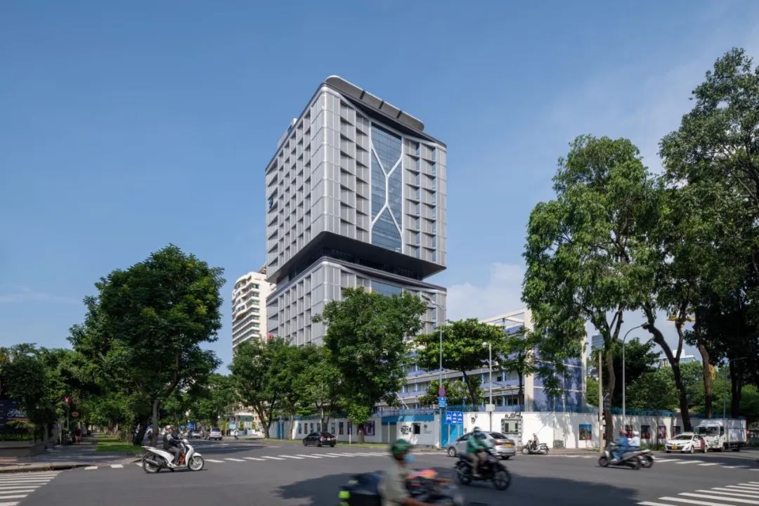 置身於胡志明市繁忙的Le Duan Boulevard，越南技商股份商業銀行以其現代與獨特的外觀脫穎而出，Foster + Partners精心設計的摩天大樓，矗立於蔚藍的天空下，成為都市風景中的一道亮麗風景線。其鋸齒形的外立面不僅是對熱帶陽光的巧妙回應，更是對環境永續與節能的深思熟慮。這棟大樓不只是一座辦公建築，它的存在代表了對未來城市生活方式的一種想象，提供了一種融合自然光與綠意空間的工作環境，促進了一種生產力與創造力共存的辦公文化。在這裡，每個角落都流淌著創新與合作的精神