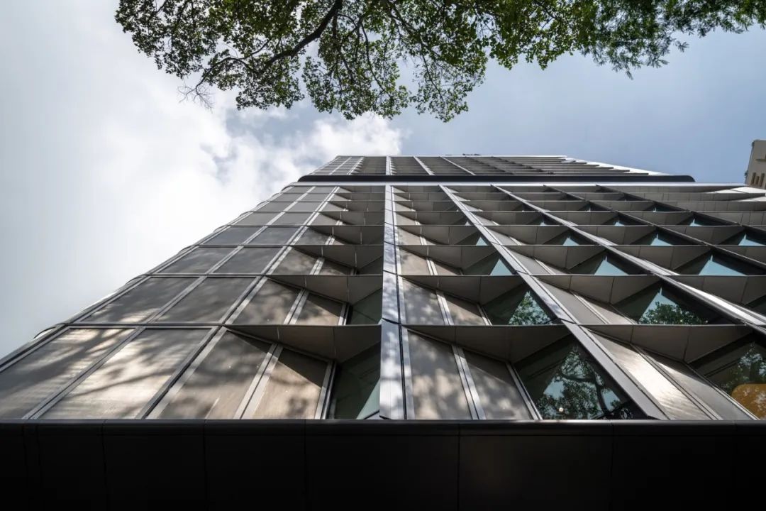 街道仰望,「Techcombank總部」大樓的壯觀形態與周圍綠蔭形成鮮明對比,它的設計巧妙地與熱帶陽光和自然環境對話。這座福斯特建築事務所設計的塔樓,其鋸齒狀的外立面在形式上創造了視覺節奏,同時在功能上則實現了自我遮陰。這些屏風般的立面不僅在內部營造了舒適的光線條件,也為城市天際線增添了動態與層次。在這塊繁華都市的土地上,大樓猶如一個現代雕塑,既是商業活動的舞台,也是工程與設計藝術的結晶