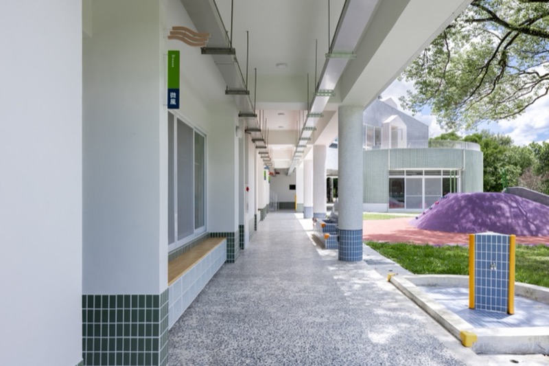 嘉義縣大埔國中小附設幼兒園 究境聯合建築師事務所 設計團隊為配合一旁國中小的校園環境,整體以灰白色調為主,在局部細部上運用了綠色和藍色的馬賽克,創造大埔鄉有山有水的環境意象