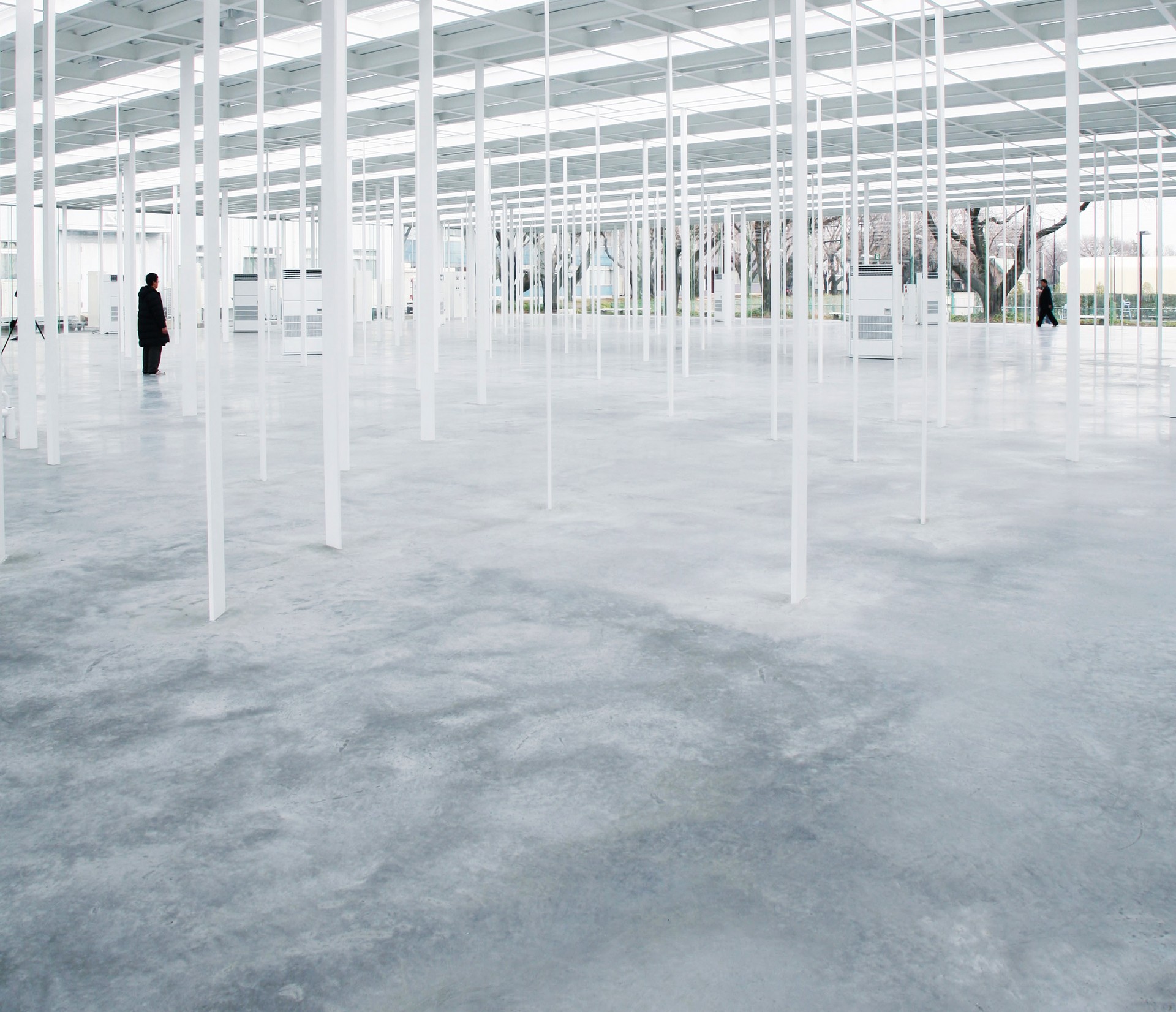 在日本神奈川工科大學KAIT工房的寬闊空間中，時間仿佛凝固。無數潔白的柱子矗立，如同密林間的樹幹，斑駁光影在其中遊走，形成一幅動靜交錯的畫面。這不只是學習的場所，更是一片充滿未來感的探索之地，人在其中行走，就像在時間和空間的交錯軸線上尋找創新與靈感的交匯點