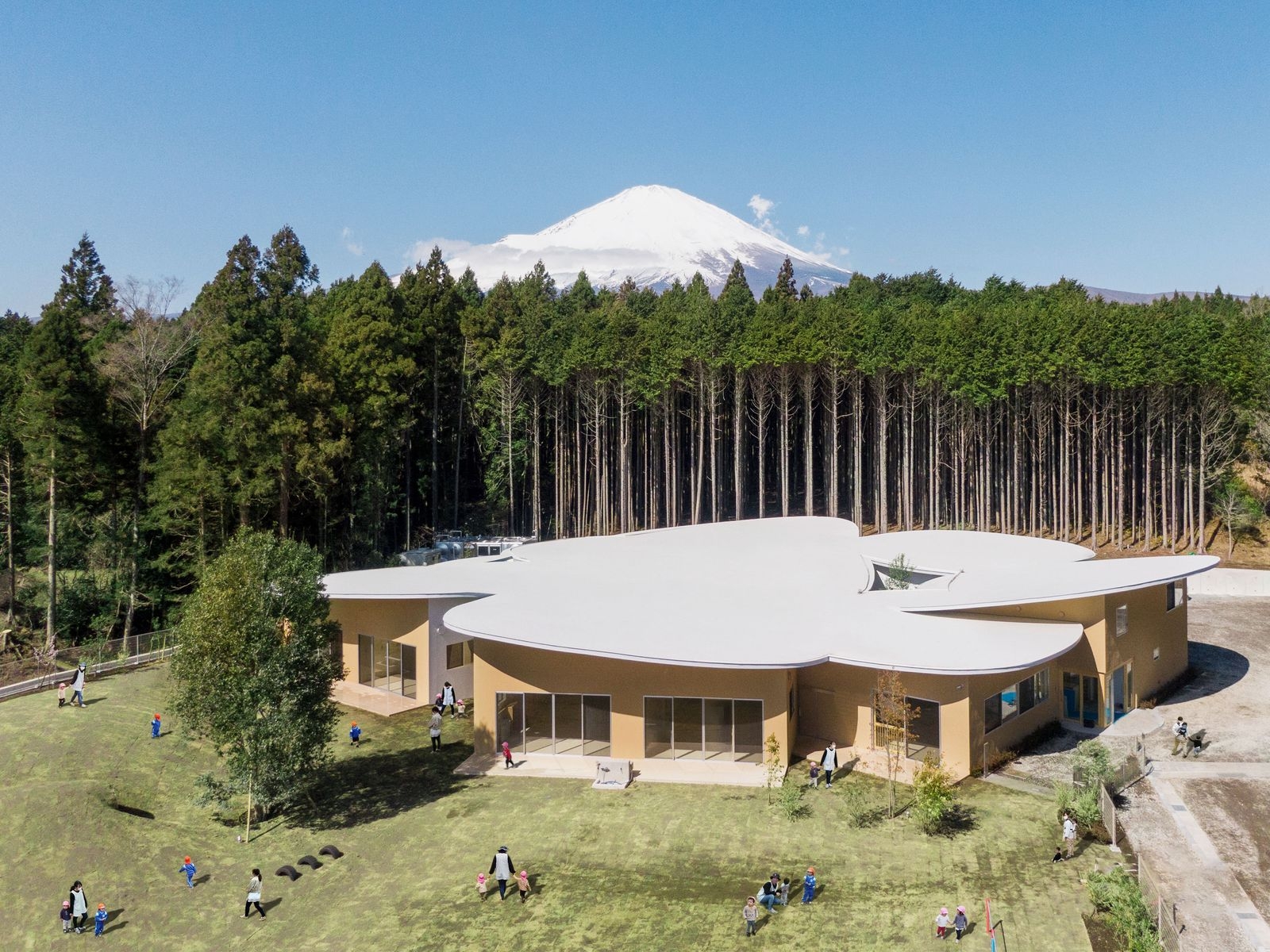 高嶺之森幼兒園位於靜岡縣御殿場市,坐落在富士山腳下,由山下貴成建築設計事務所設計。園舍屋頂如花瓣綻放,周圍環繞茂密森林。孩子們在廣闊的綠地上嬉戲,感受四季的變遷與不同氣息。這裡的設計充分考慮到兒童的需求,提供了一個充滿活力與創意的學習環境 與富士山共舞的兒童樂園!靜岡縣「高嶺の森のこども園」幼兒園:讓孩子在四季更迭中感受自然的美麗/山下貴成建築設計事務所
