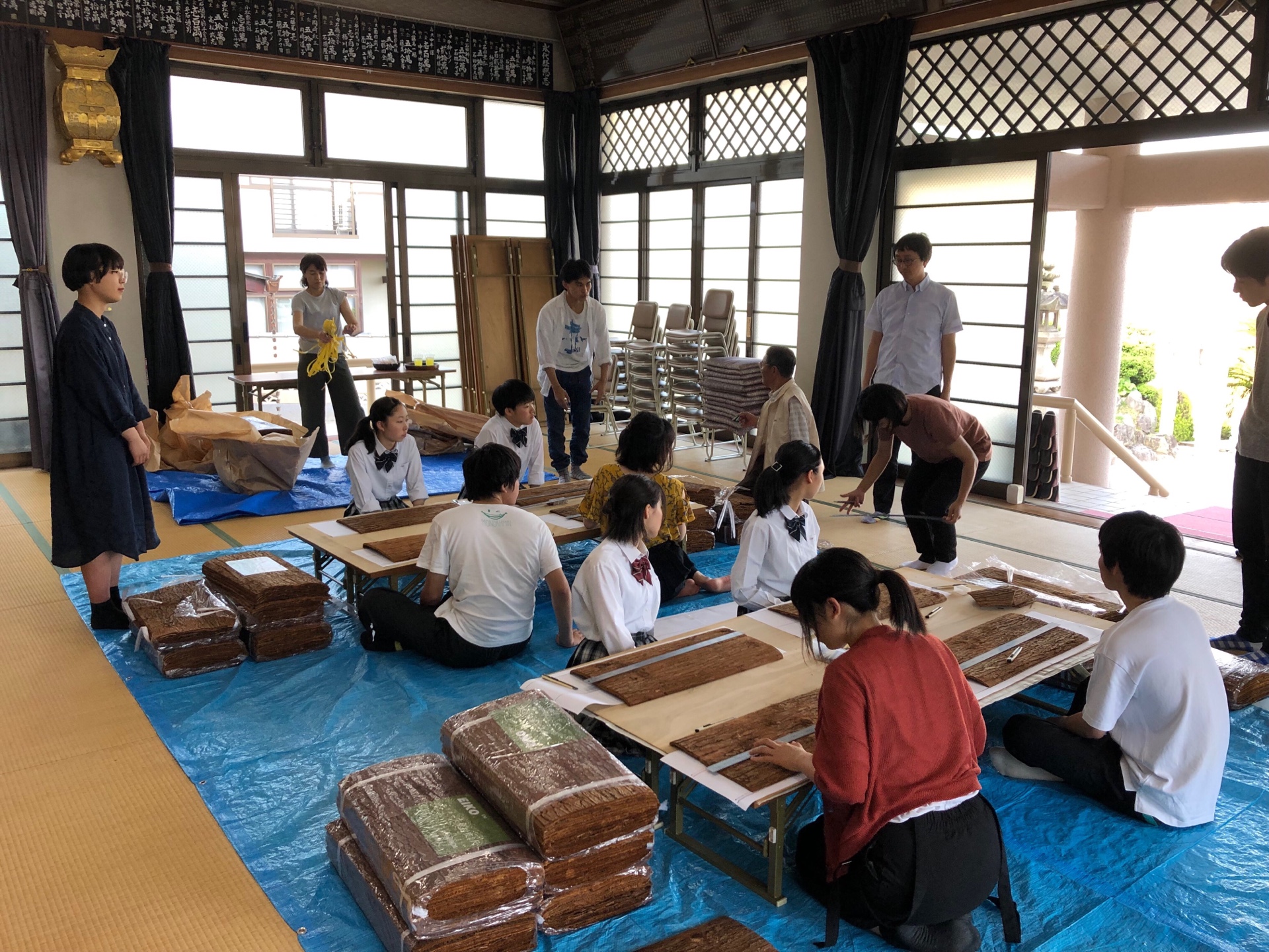 大西麻貴和百田有希邀請了吳工業高等專門學校的學生參與，一同在工作坊中手工切割杉皮