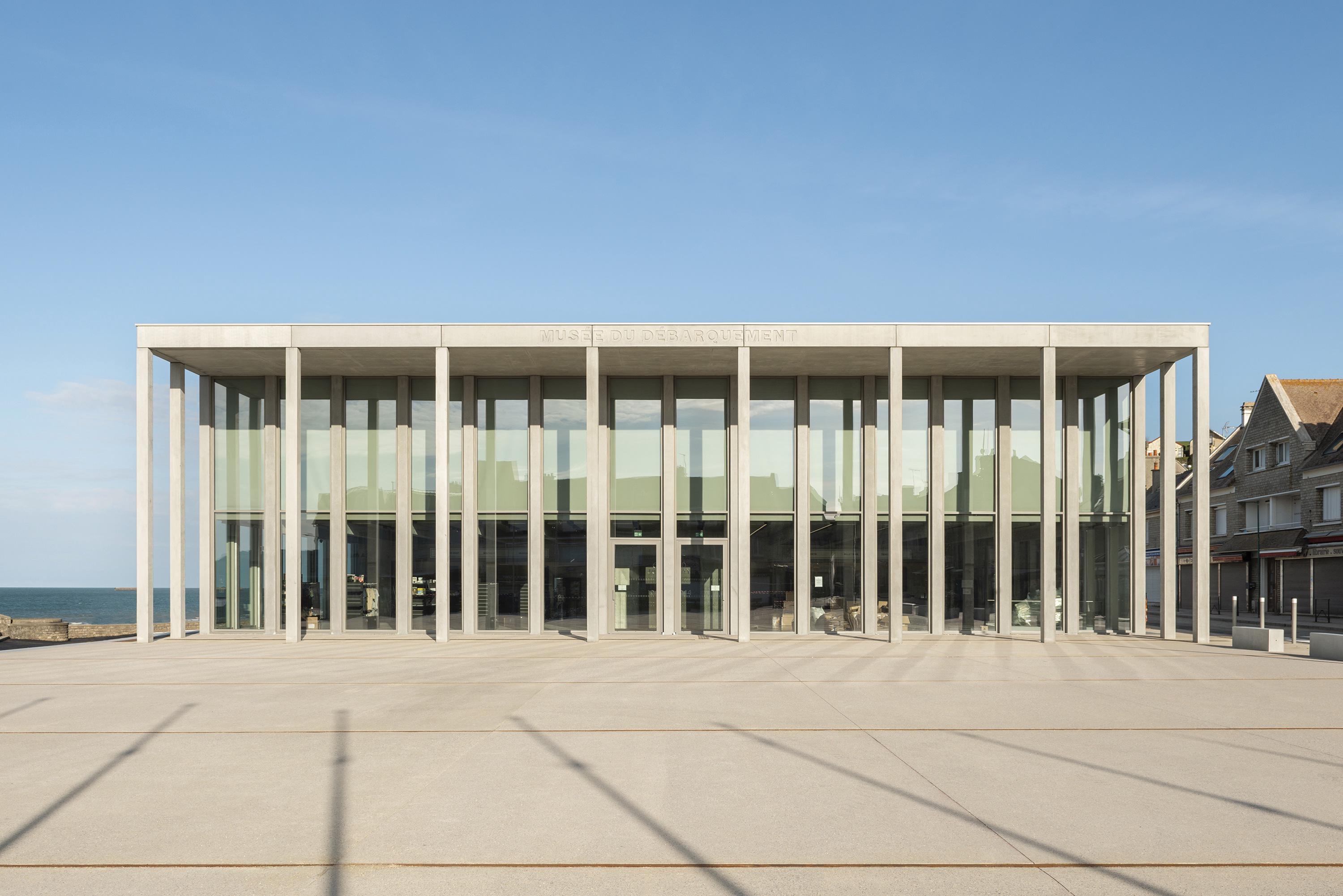 PROJECTILES, Antoine Cardi · D-Day Museum 阿羅芒什的D-Day博物館前院，不僅凸顯博物館本身，更是一個絕佳的觀景點，讓遊客能在此欣賞潮汐漲落間所顯露的歷史遺跡。這片廣場向東延伸，與新建的樹林公共空間相連，與紀念1944年6月6日諾曼第登陸的「6月6日廣場」形成互補與延續的關係。新增的看台進一步完善了整體佈局，讓這片區域成為一個多功能的公共空間