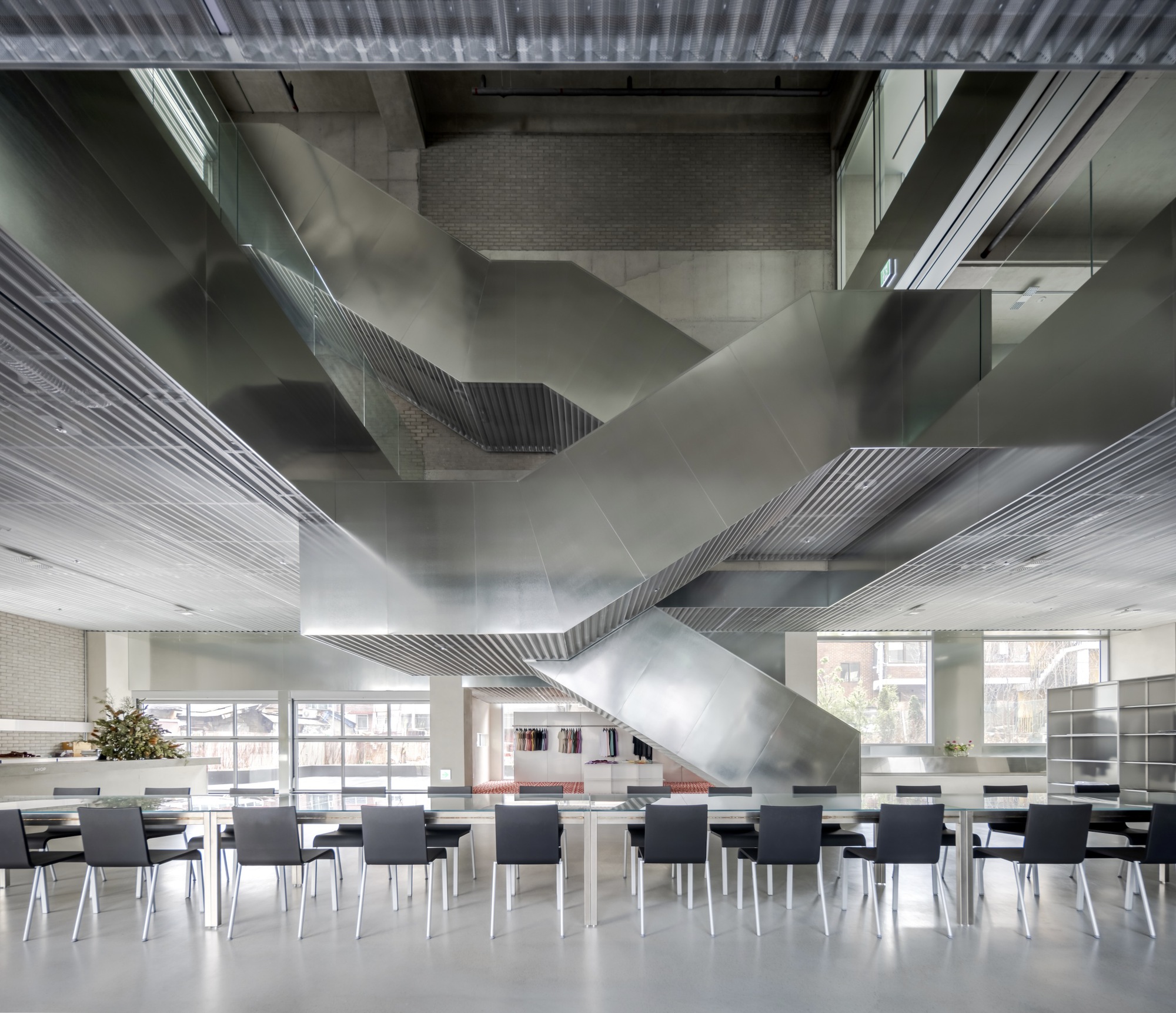 Behet Bondzio Lin Architekten 林友寒 韓國首爾W-Mission企業總部 銀色樓梯宛如藝術品，錯層設計引人入勝。寬敞明亮的開放區域，配以簡約現代的家具，展現品牌追求卓越與創新，提供了舒適而高效的工作環境