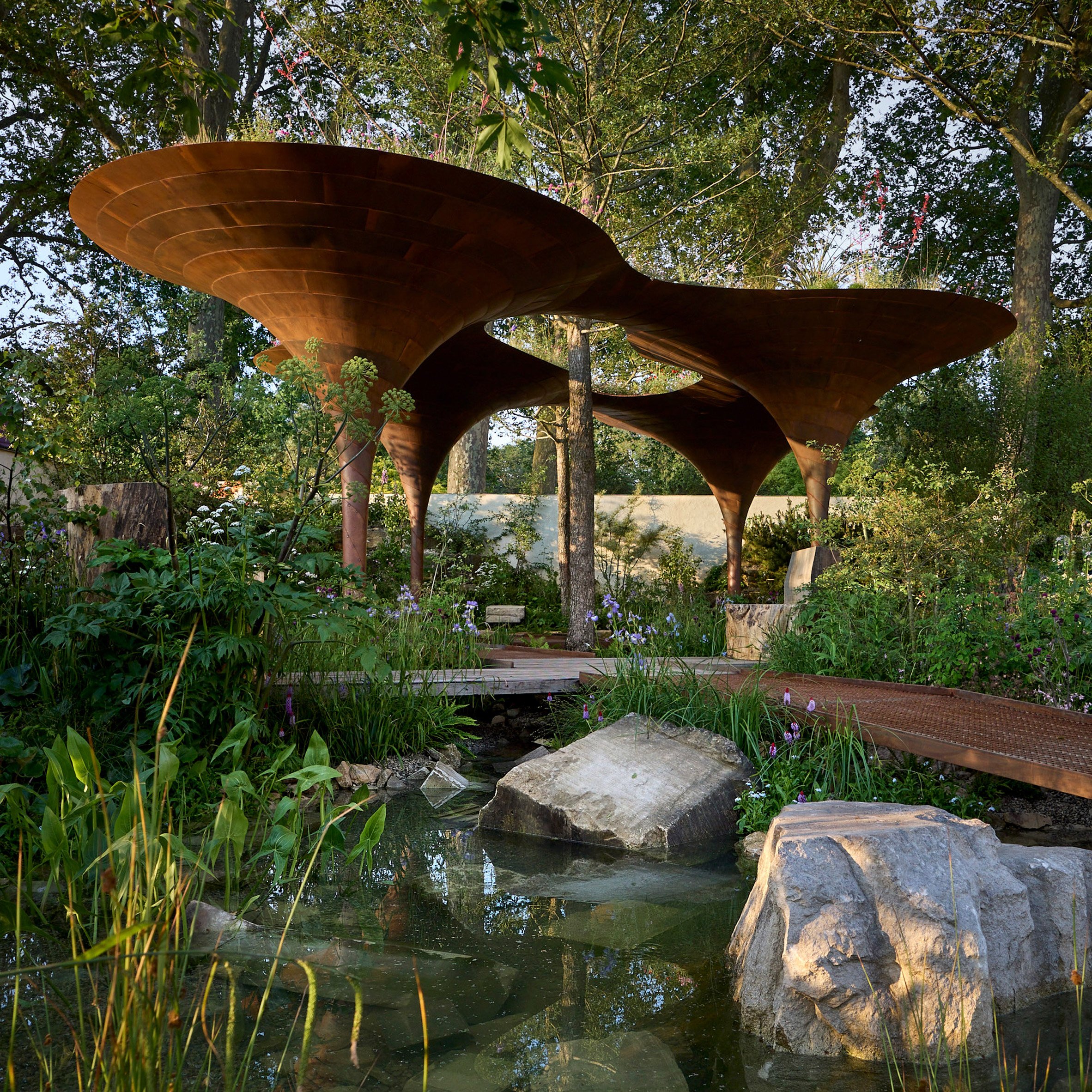 WaterAid 雨水收集綠建築 倫敦切爾西花卉展 RHS Chelsea Flower Show Je Ahn Tom Massey 巧妙地融合了自然與現代元素,雨水收集亭不但能夠有效收集和儲存雨水,還可以通過過濾系統淨化水質,為園內植物提供灌溉用水。亭子周圍布滿各種適應不同水量需求的植物,展示了氣候變遷下的生態韌性,這些設計不但能夠提高公眾對水資源管理的認識,更是強調了環境保護的重要性