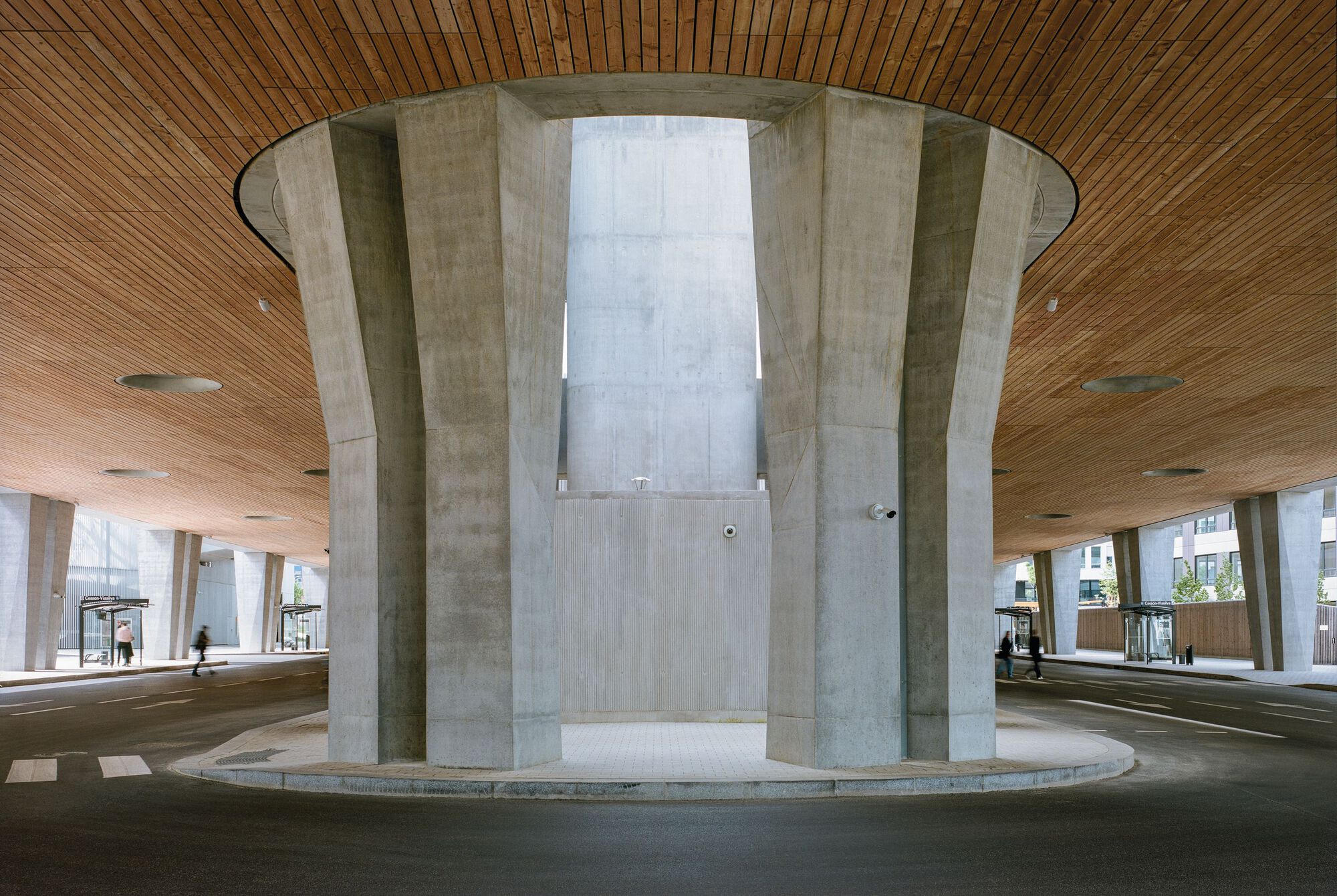 法國 Cesson - Viasilva (métro de Rennes) 捷運地鐵站 Ateliers O-S architectes 清水混凝土柱形成宏偉的圓形結構,支撐著落葉松木材質的天花板,營造出溫暖舒適的氛圍。中央區域的開放設計不僅提供自然採光,也創造了視覺焦點。周圍的巴士站和人行道展現了這座建築的多功能性