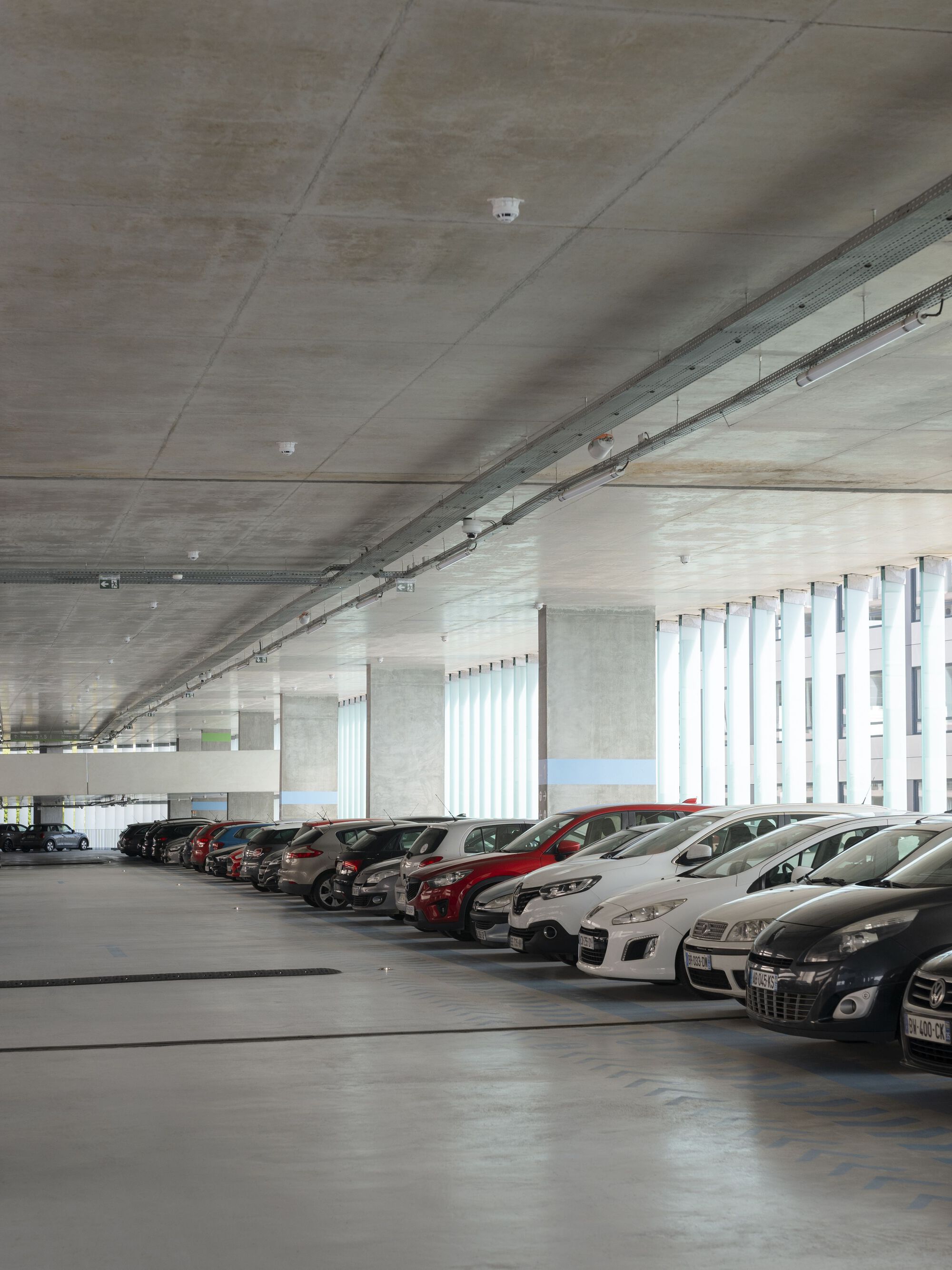 法國 Cesson - Viasilva (métro de Rennes) 捷運地鐵站 Ateliers O-S architectes  Cesson-Viasilva多功能轉運站的室內停車場：乾淨整潔的環境結合現代化設施，顯示了建築師在設計中對於功能性與實用性的重視，透過寬敞的停車空間，服務於當地居民，強調未來發展的靈活性與環保理念