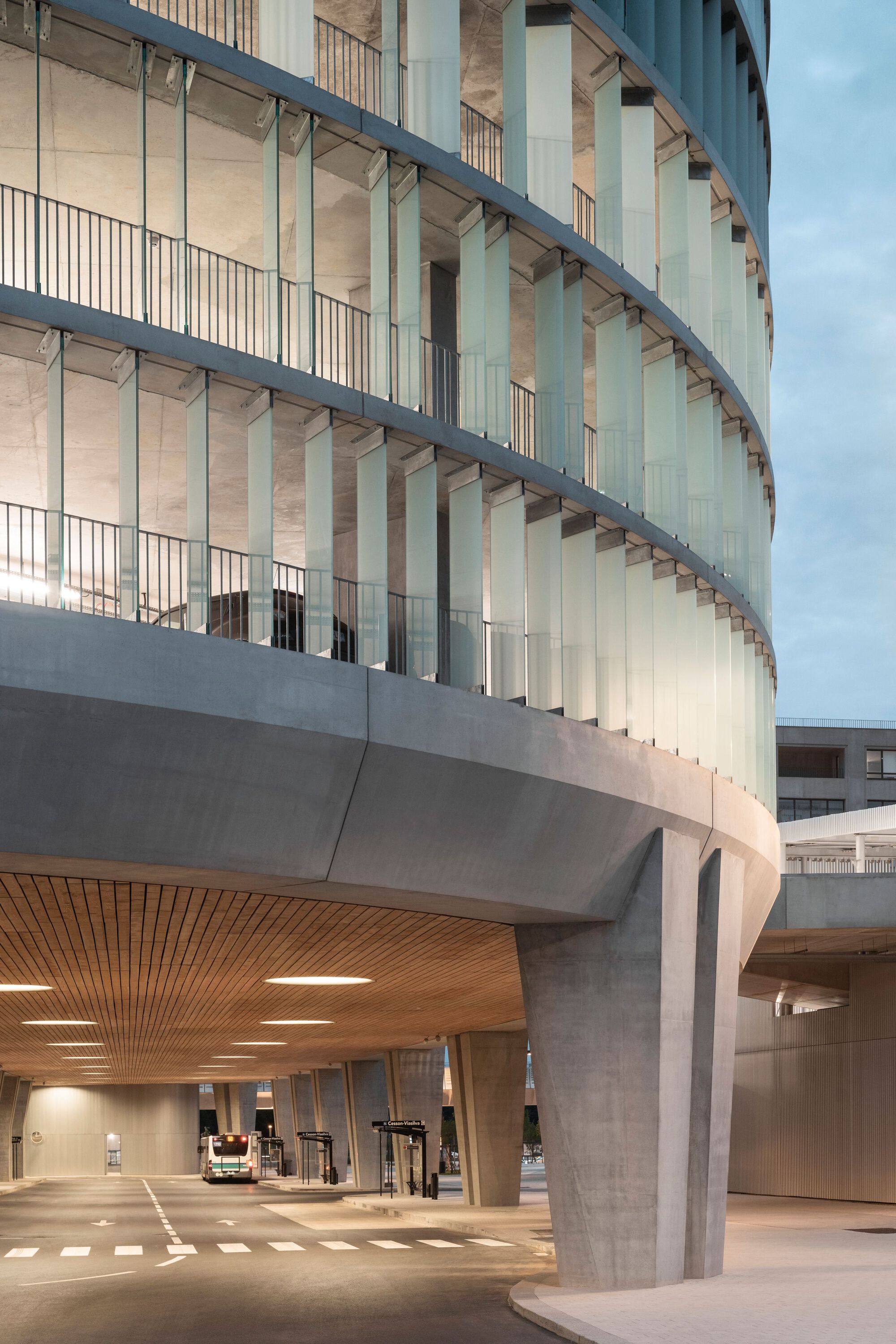 法國 Cesson - Viasilva (métro de Rennes) 捷運地鐵站 Ateliers O-S architectes  法國 Cesson - Viasilva 捷運車站弧形的外觀以玻璃和清水混凝土為主要材料，展現出現代感與優雅。多層的結構和透明的欄杆創造出開放感，而地面層的木頭天花板則為空間增添溫暖