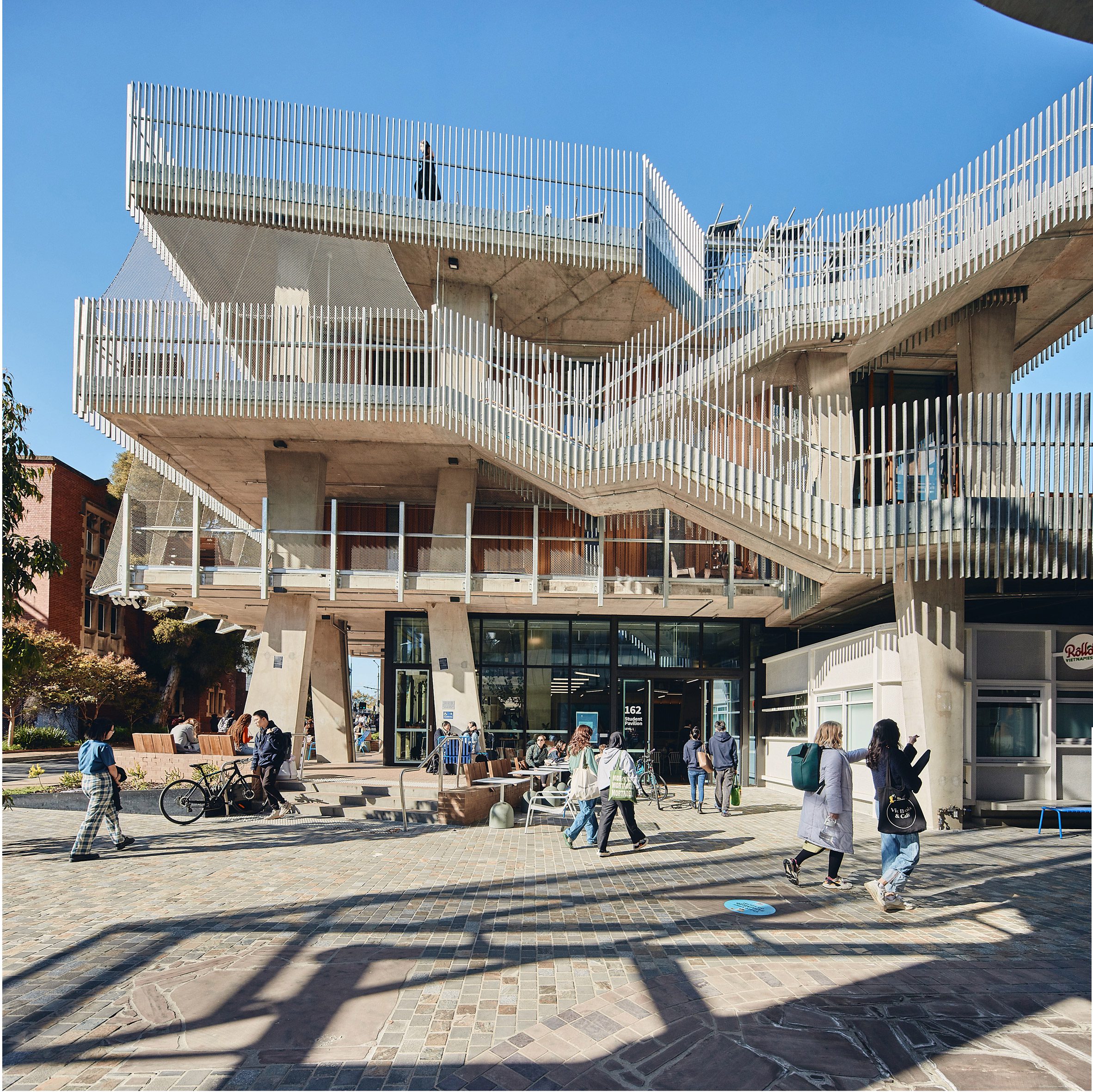 University of Melbourne Student Pavilion by KoningEizenberg 澳洲墨爾本大學 學生活動中心 清水模 清水混凝土 建築的外立面運用了鋼製網狀結構來保護高層陽台，這種設計不僅提升了安全性，還保持了建築的通透感，避免了封閉式設計帶來的壓迫感。此外，根據澳洲的地理位置，設計團隊在北立面使用了較小比例的窗牆比，來減少強烈的日曬。相反地，南立面則採用了大面積的玻璃，使自然光得以充分滲透，為學生提供了舒適的學習環境