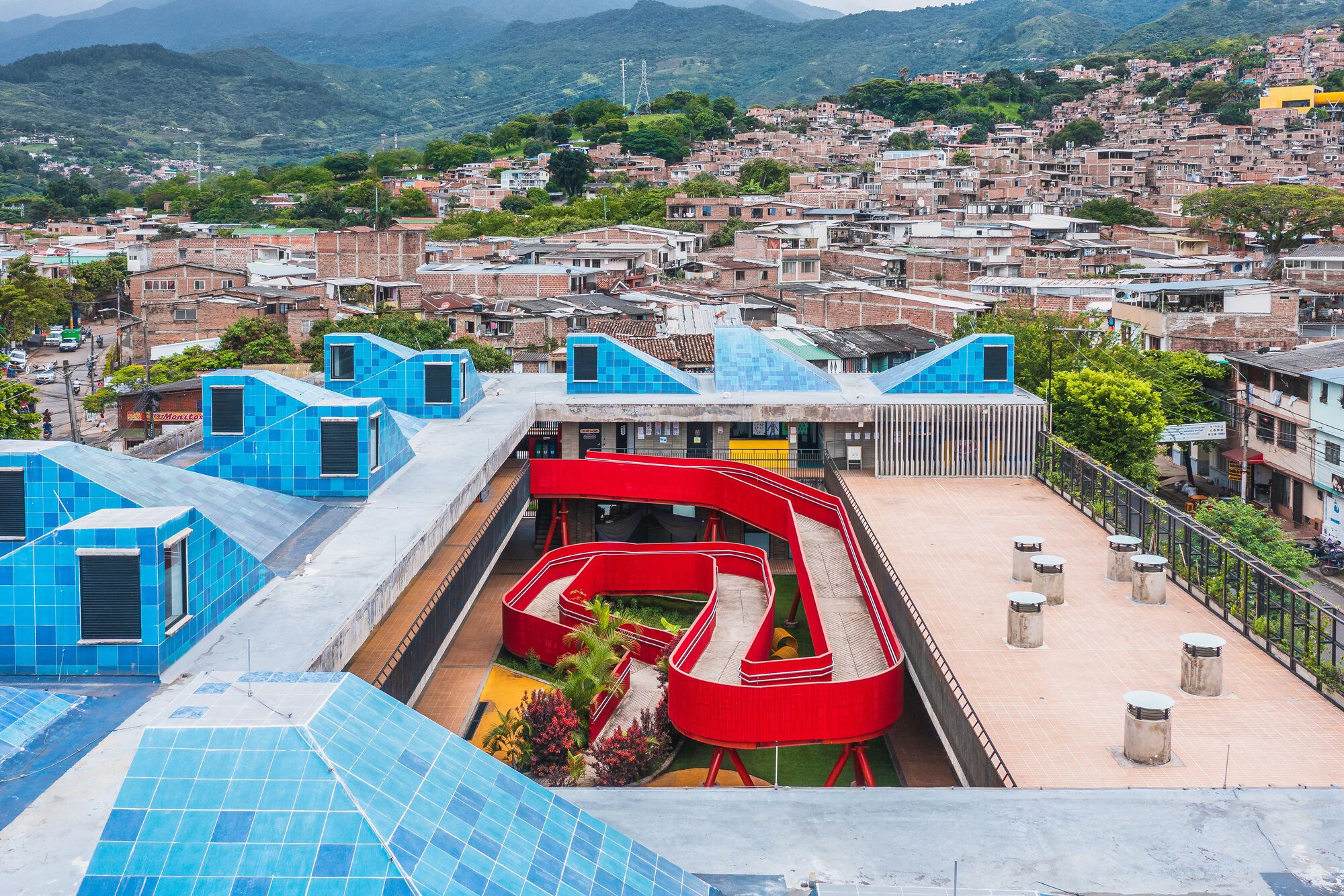 天窗錯落有致，在建築量體上勾勒出變化的輪廓，色彩計畫以藍色、黃色、紅色等高彩度的飽和色，與社區形成互視效果，使其成為社區中辨識度極高的地標