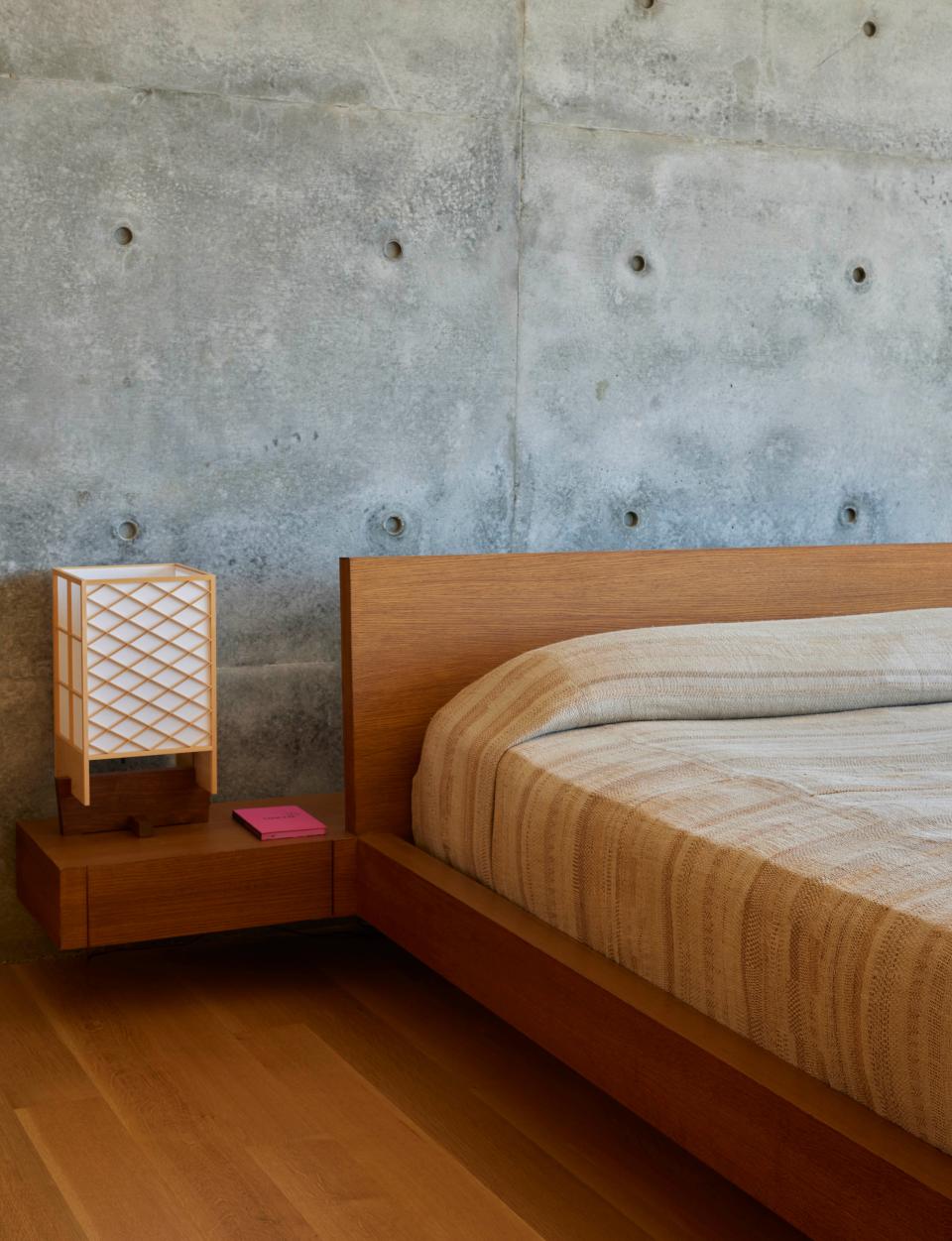 在主臥室中，櫻製作所生產的 George Nakashima 桌燈放置於 Studio O by Oliviero Baldini 設計的定制床架上