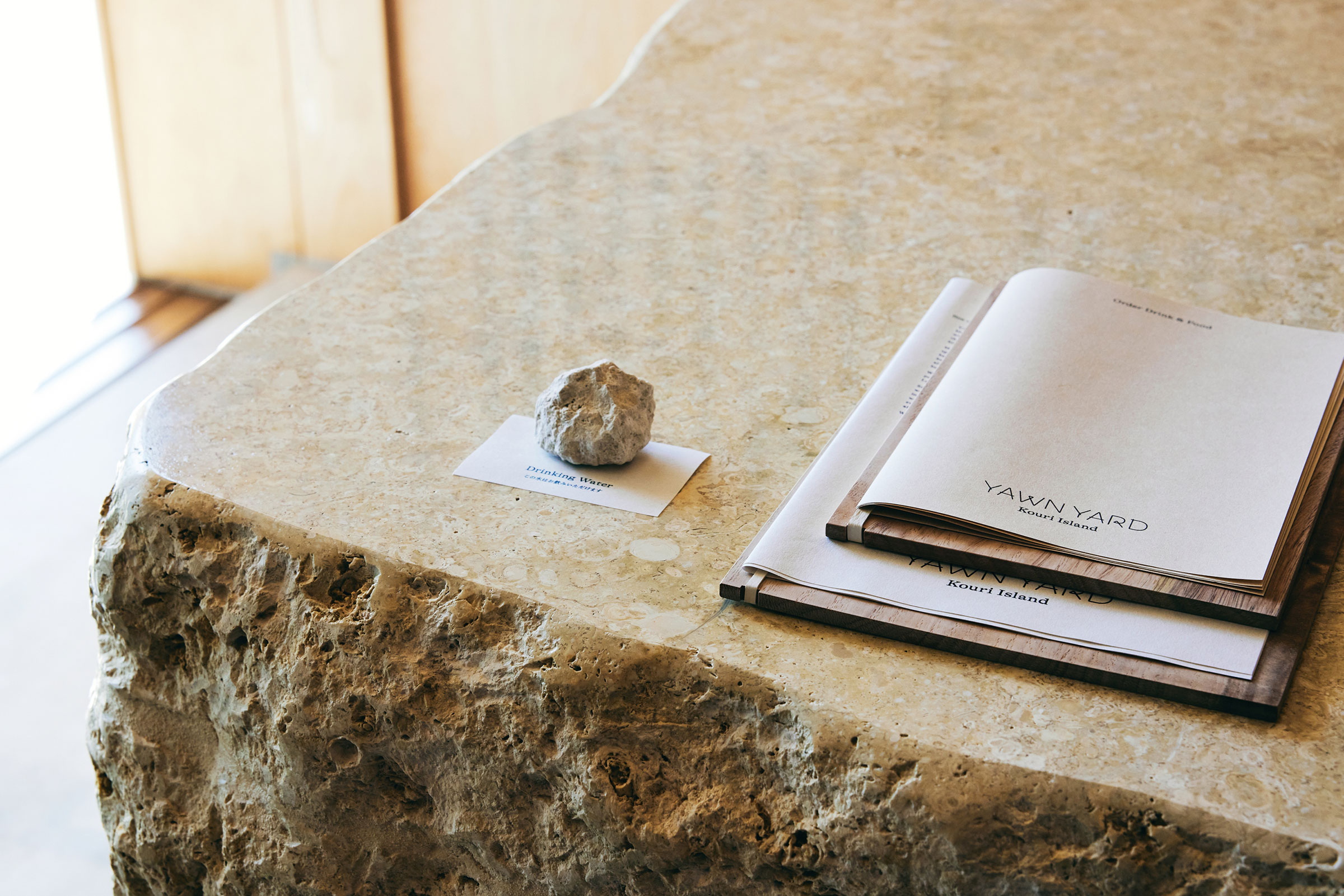 AWN YARD Kouri Island 在家具的選擇和設計上，也融入了許多沖繩的在地元素。例如，接待櫃檯使用了琉球石灰岩，而矮桌則是由紅磚砌成，這些家具都與當地工匠合作，展現了琉球的傳統工藝和特色