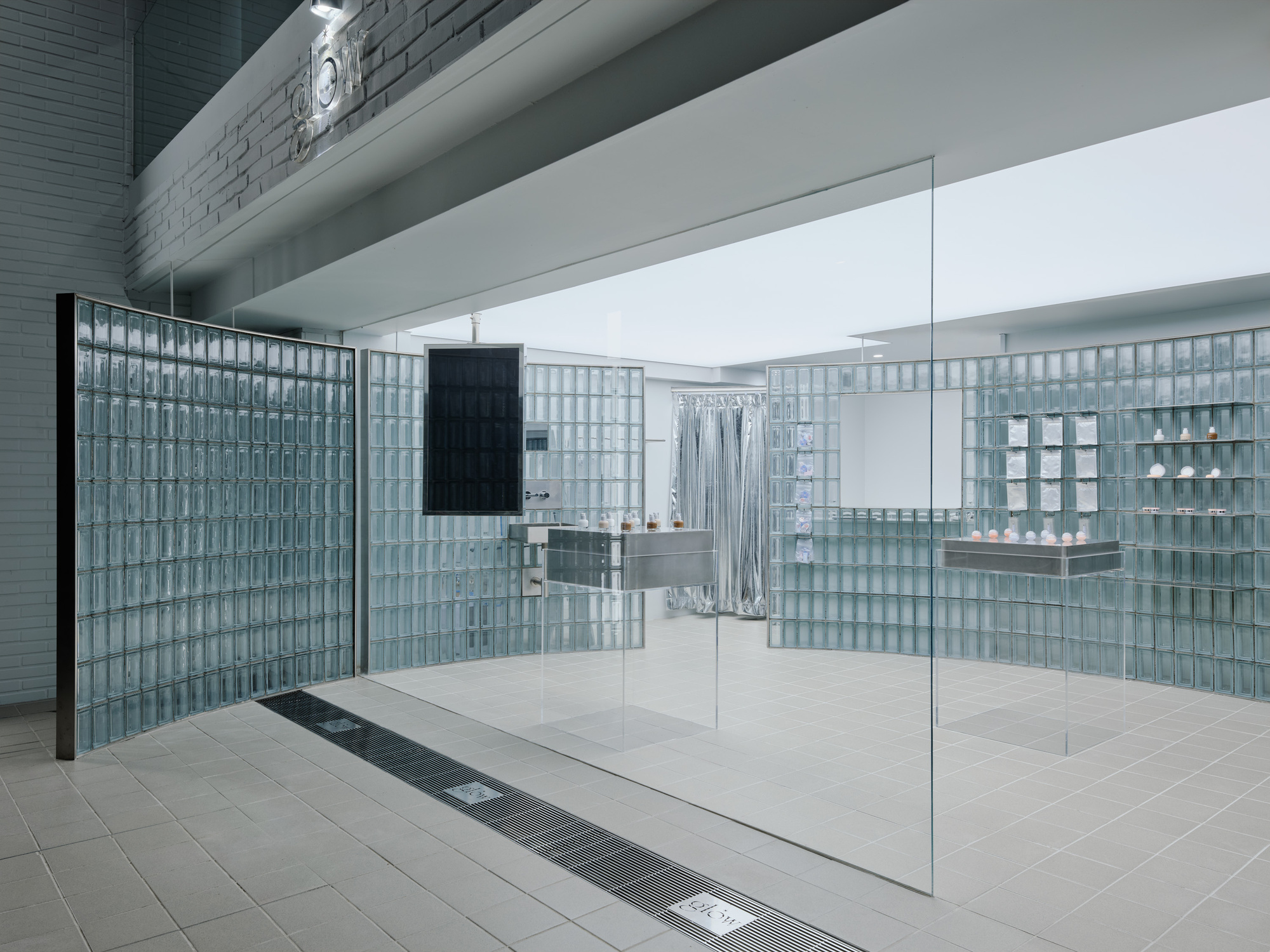 展示間內一項重要的建築元素是彎曲的玻璃磚隔間,從遠處就能引導人們的視線自然地進入空間。此隔間除了美觀上的價值外,也具備實際的功能,巧妙地將展示間劃分為顧客與員工動線等不同區域