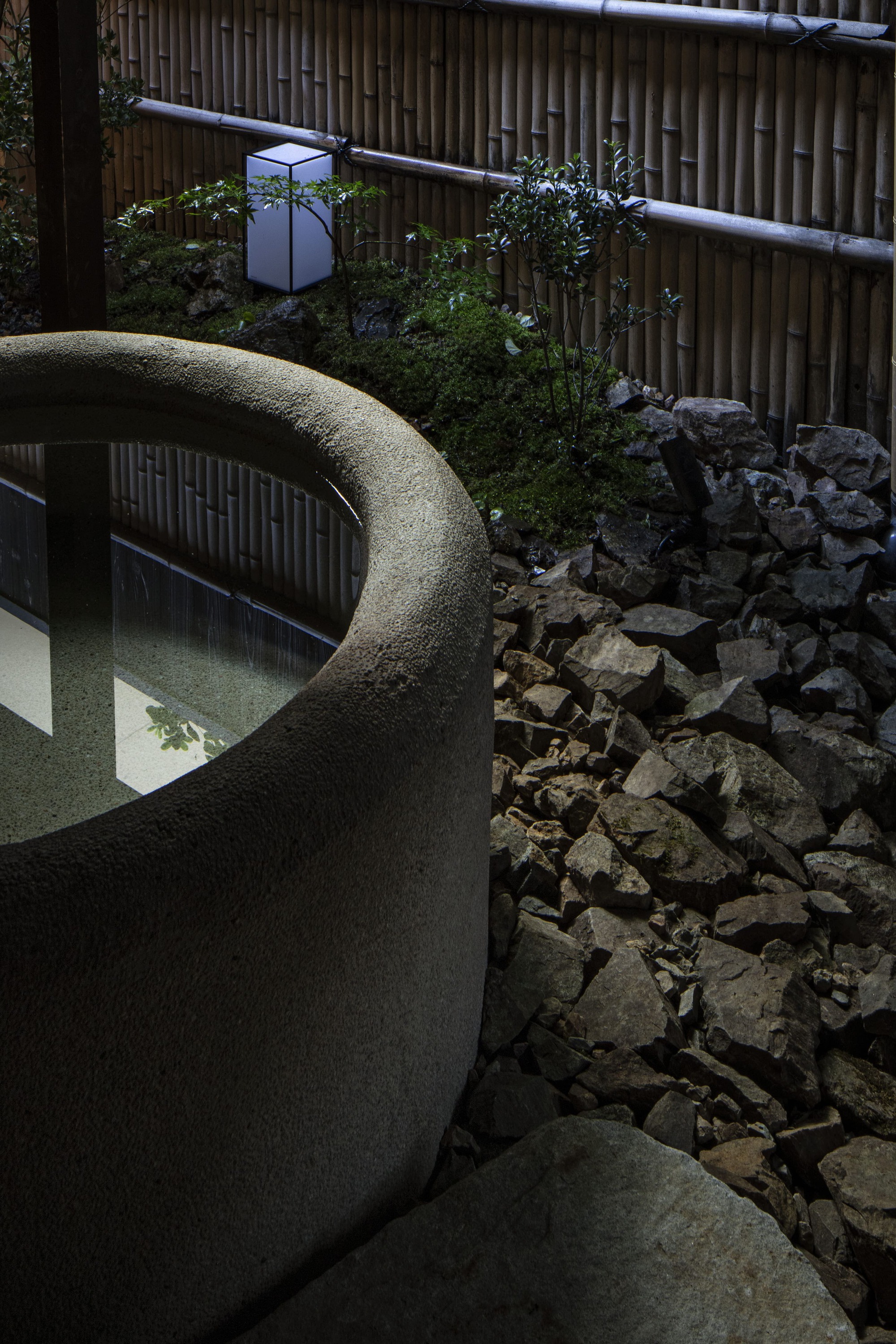 Nazuna Kyoto Higashihonganji 京都 旅館 東本願寺 STUDIO ALUC 水鉢靜置於碎石與苔蘚之間,竹籬笆圍塑出內向庭院,方形行燈低調投射光影,微光間感受町家深處的時間靜謐與細節深度