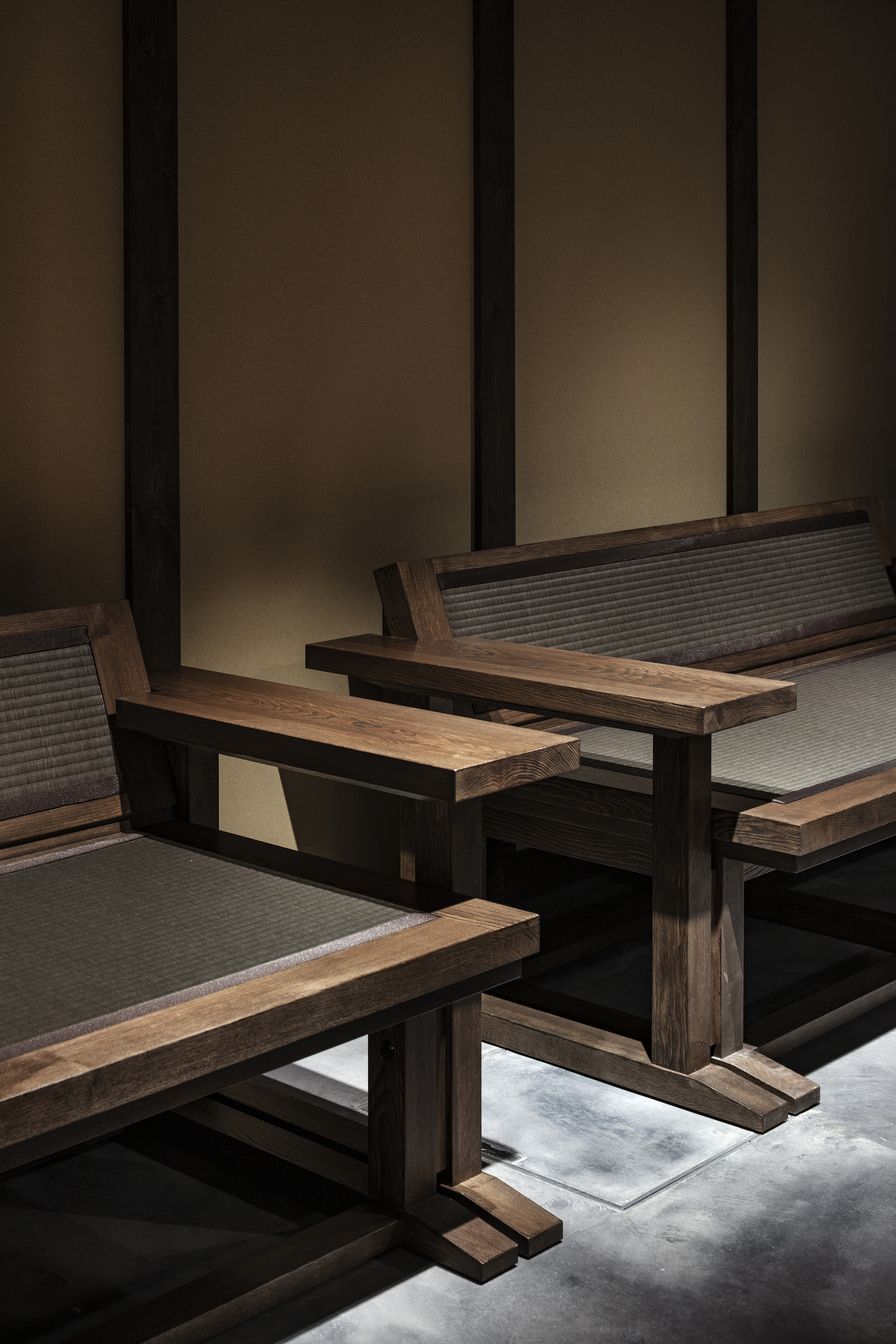 Nazuna Kyoto Higashihonganji 京都 旅館 東本願寺 STUDIO ALUC 實木結構椅座以塌塌米編織面呈現,日本傳統材質語彙轉化為當代家具形式,置於拋光水泥地與塗壁構成的深色基底之中