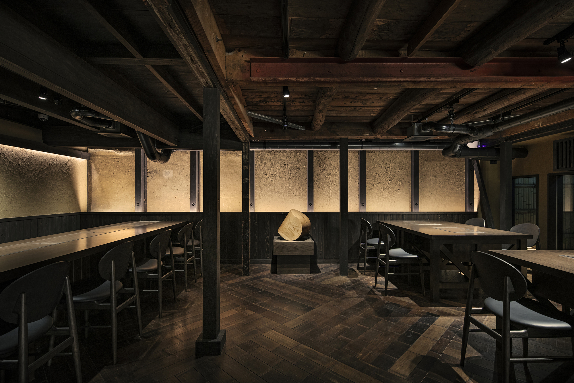 Nazuna Kyoto Higashihonganji 京都 旅館 東本願寺 STUDIO ALUC 裸露梁柱與深色木地板構築低天花空間,中央陳列的木雕作品打破對稱秩序,沉穩家具語彙襯托出修舊空間中的當代節奏