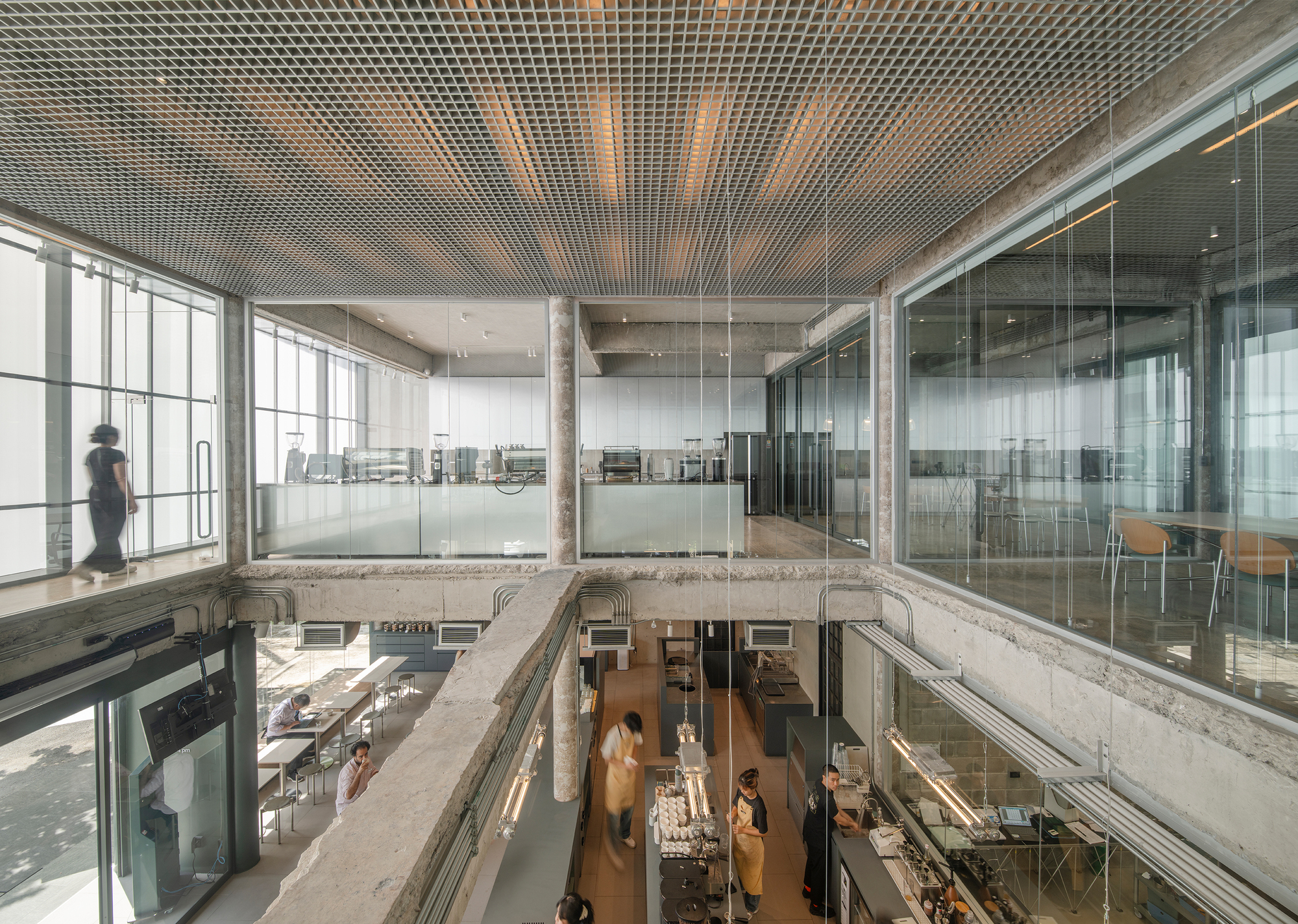 TasteSpace 室內設計 泰國曼谷冠軍咖啡店「Factory Coffee」室內設計以裸露混凝土、玻璃隔間和金屬格柵天花營造俐落感，設置簡約吧台與座位區，顧客能近距離欣賞咖啡製作全過程