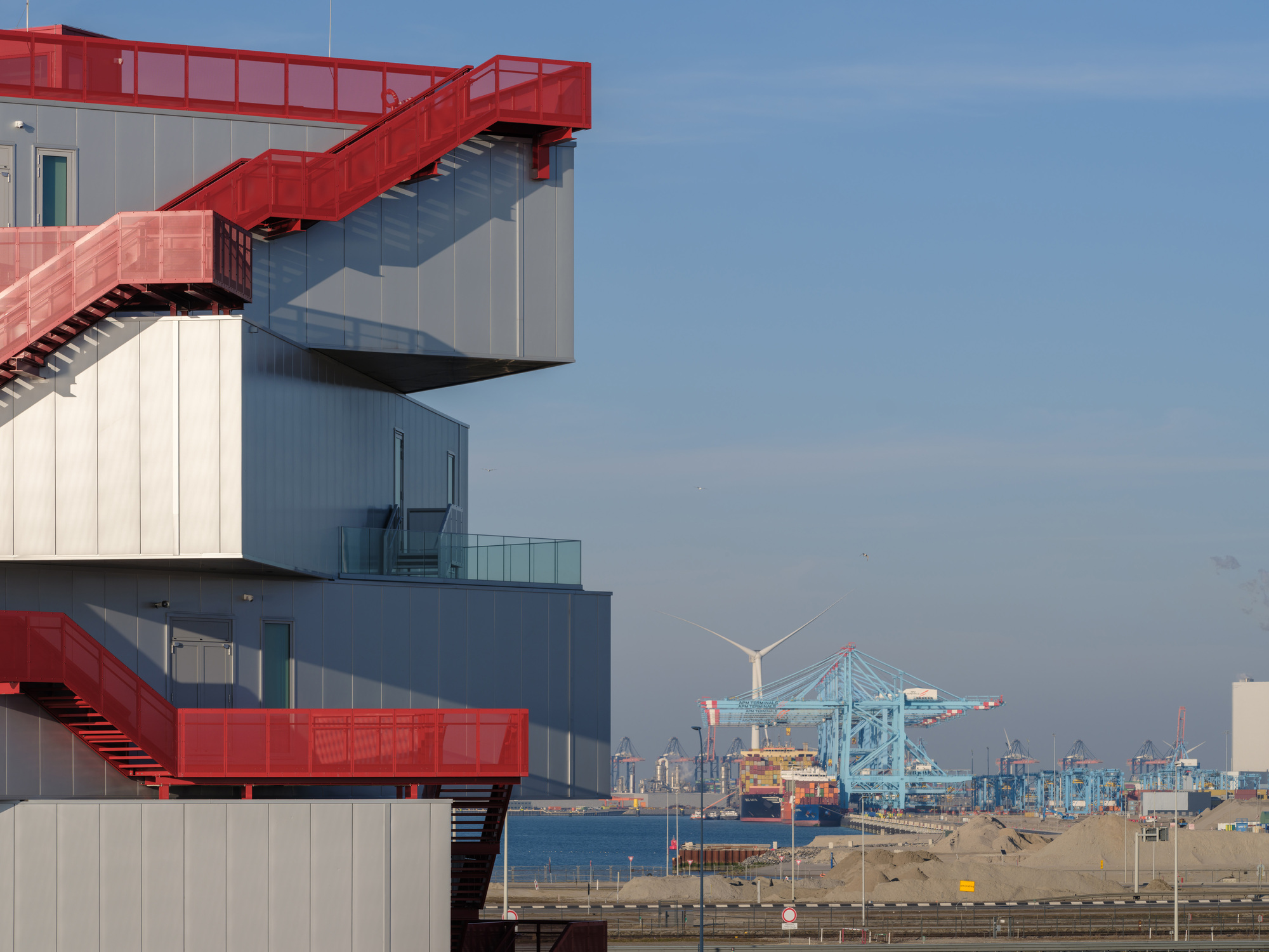 坐落於港口 Maasvlakte 2 人工填海區的沙灘上,Portlantis 佔據顯眼位置,成為遠方即可見的地標。其教育功能採務實、直接的態度,藉由簡潔的機能性、戲劇性的造型以及工業建材,傳遞港口精神。建築造型直接回應內外的活動需求:每層樓的平面皆為方形,設有一面大面積全景窗,框住特定的外部景觀。各樓層的朝向及其主窗位置皆對應其功能:例如一樓的咖啡廳,窗戶朝向西方,能欣賞沙丘的親密景緻;而位於四樓的餐廳,則可眺望北海的夕陽與夜間港口天際線的燈火。