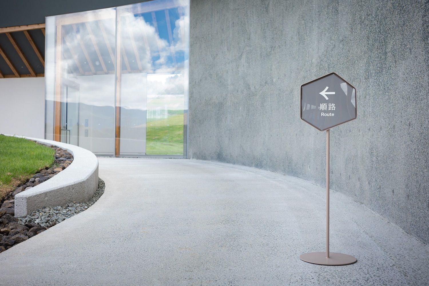 Kumamoto Earthquake Museum KIOKU熊本地震 震災ミュージアム KIOKU 混凝土牆面與地板的處理，特別選用傳統的水洗石（洗い出し）工法或噴砂（ショットブラスト）處理，藉此凸顯阿蘇地域常用的山鹿（Yamaga）產天然骨材的樸實色澤與質感。屋頂更鋪設了特別訂製的窯燒磁磚，其釉料配方獨特，混合了當地草原維護定期燃燒（野焼き）所產生的灰燼，以及阿蘇特有的黃土，呈現獨一無二的在地色彩