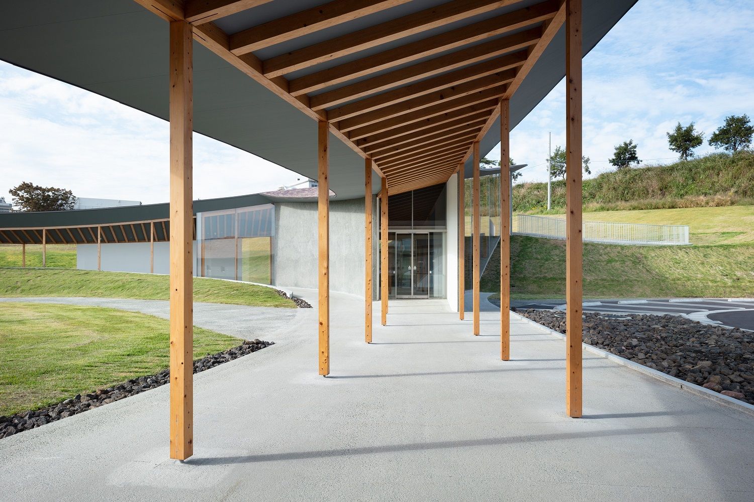 Kumamoto Earthquake Museum KIOKU熊本地震 震災ミュージアム KIOKU 建築結構系統展現木與地方連結的理念。屋頂的構架主要採用熊本縣當地盛產的杉木與檜木構築而成,溫潤的木頭調性為空間帶來安定感。水平方向的地震力則由鋼筋混凝土(RC)牆體承擔,形成穩固的混合構造,部分跨距較大的區域輔以鋼骨結構