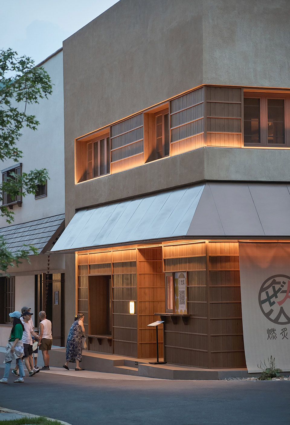 燃炙屋:坐落在轉角的日式烤肉店延續了街巷質樸的市井氣息。建築立面以水洗石塗料為基底,搭配老木板和金屬屋簷,勾勒出簡潔的幾何輪廓,入口處開放式售賣檔口成為街巷的有機組成部分,與社區鄰裡形成互動。餐廳5米高的挑空區域提供了開闊的空間視野和充足的室內採光,當陽光從一側照進餐廳,溫暖的山居記憶構築在升騰的煙火氣中