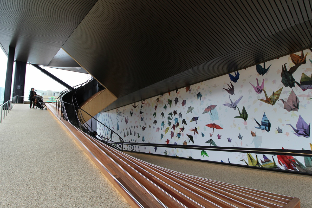 12樓「千紙鶴廣場」運用數位內容技術，打造以千紙鶴、摺紙為主題的體感互動樓層，讓遊客在遊戲中領略日本傳統文化魅力。高約50公尺的玻璃牆面「千紙鶴之壁」，讓遊客可從12樓投入親手摺製的千紙鶴，這些承載心願的紙鶴將為牆面增添繽紛色彩