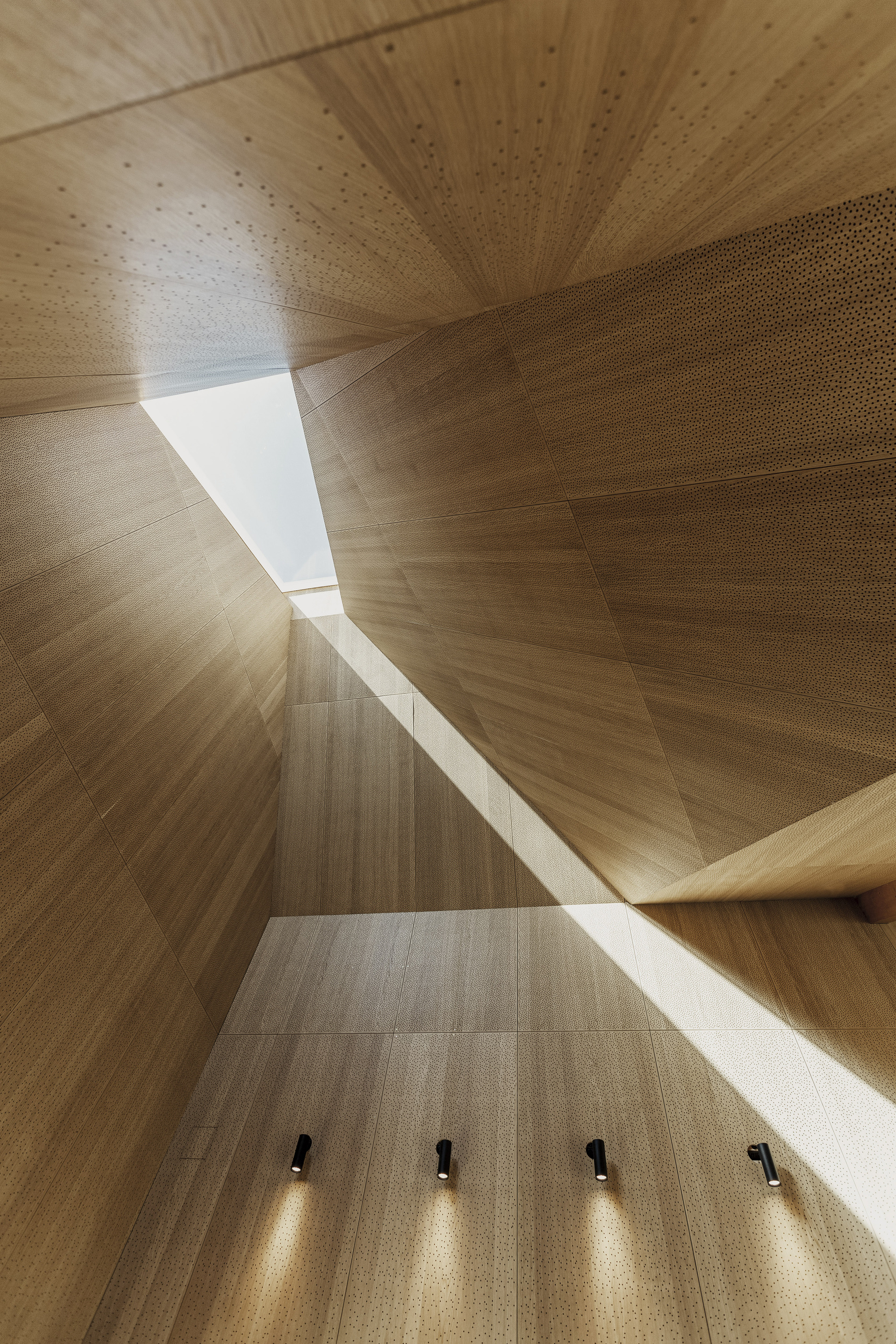 Hjørring Denmark House of Grain｜Kornets Hus 丹麥遊客中心 Reiulf Ramstad Arkitekter 兩座拔地而起的磚砌光井，它們宛如現代版的「潘森農神殿北歐紅」（Pantheon Nordic Red）光塔，巧妙地重釋了傳統麵包窯的古老意象 。傳統窯爐為幽暗高熱的轉化之所，在此卻昇華為引進天光的明亮空間，象徵著知識的啟迪与文化的開敞