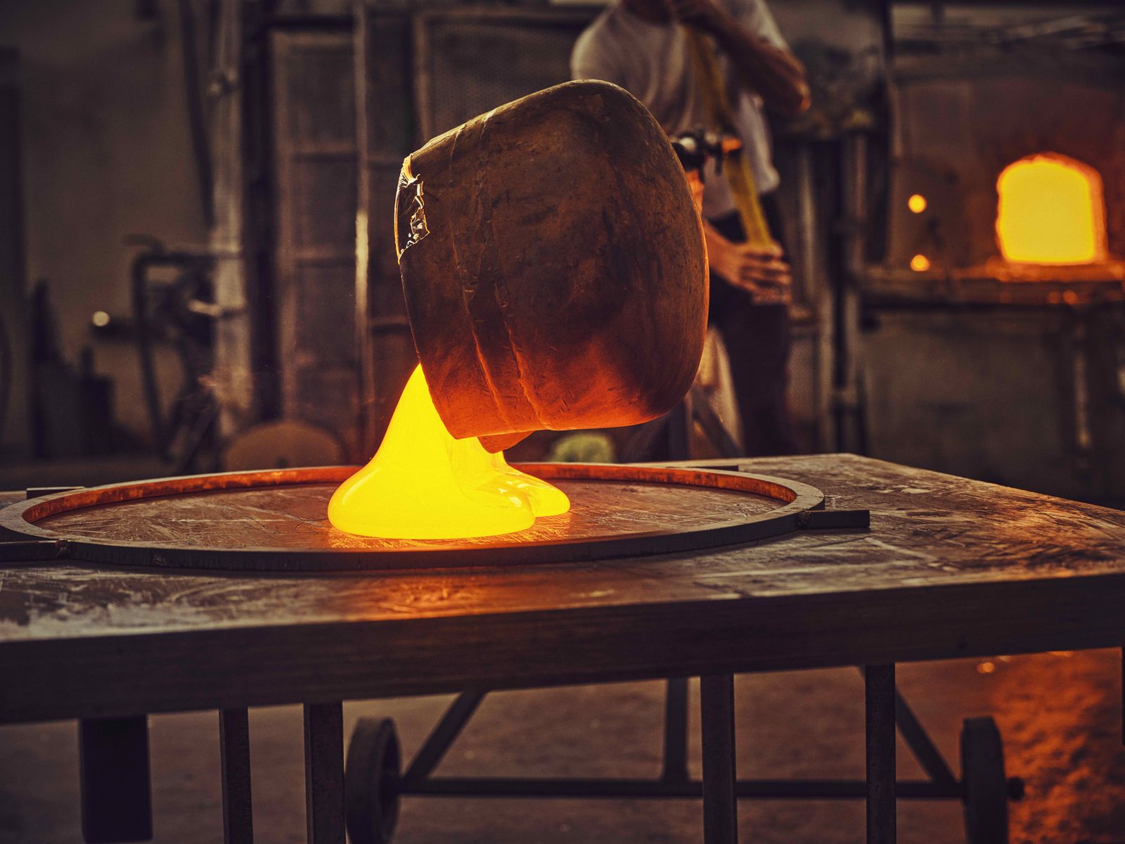 一位穆拉諾工匠將熔融玻璃倒入圓形模具中，製作展館的天花板元件（圖片來源：©Rolex/Sébastien Agnetti）