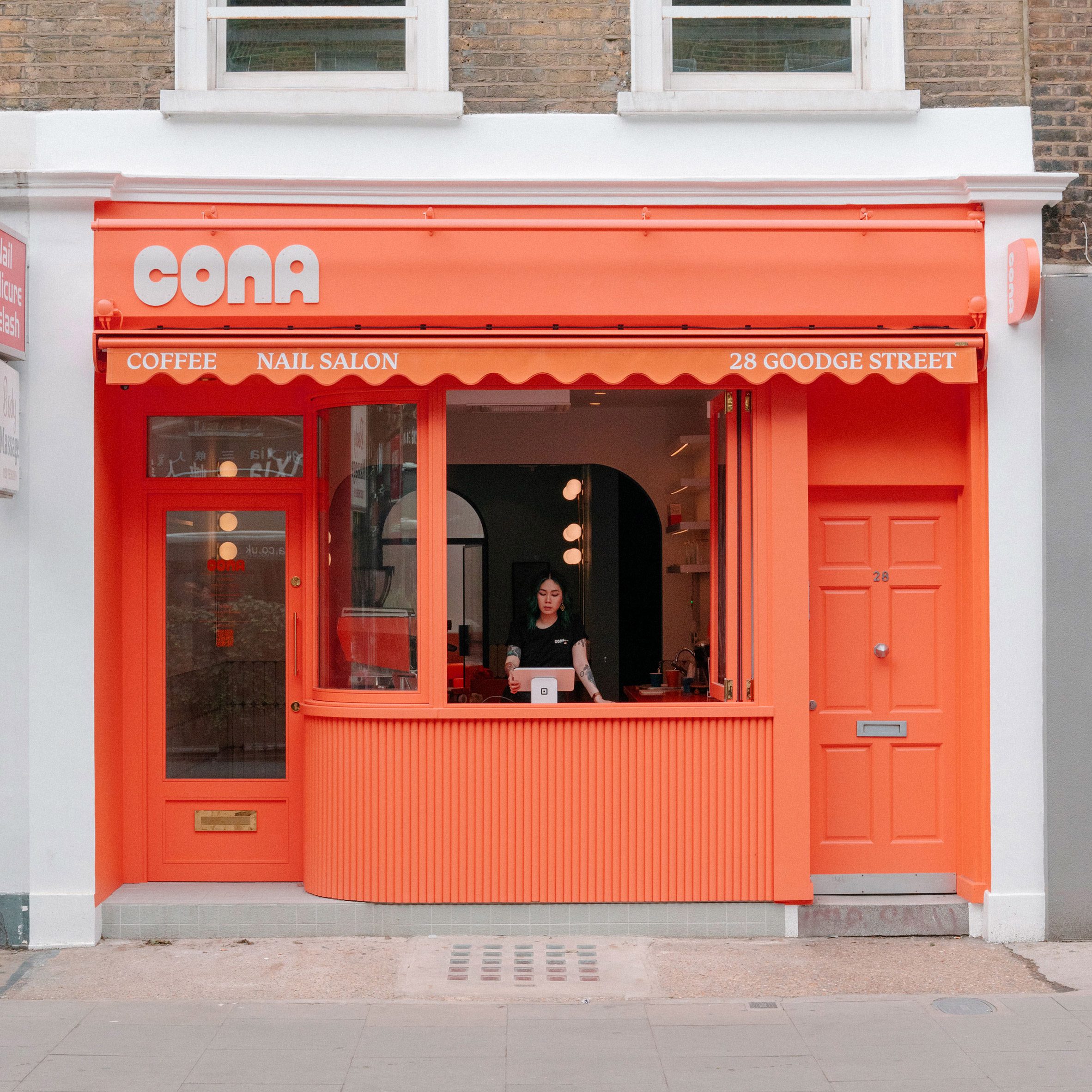 英國倫敦室內設計 Goodge 複合店Cona Tigg Coll 外觀以鮮豔的珊瑚橘色作為店面主視覺,醒目色彩與白色字體標誌構成強烈對比,圓弧窗框設計,展現年輕活潑的品牌性格