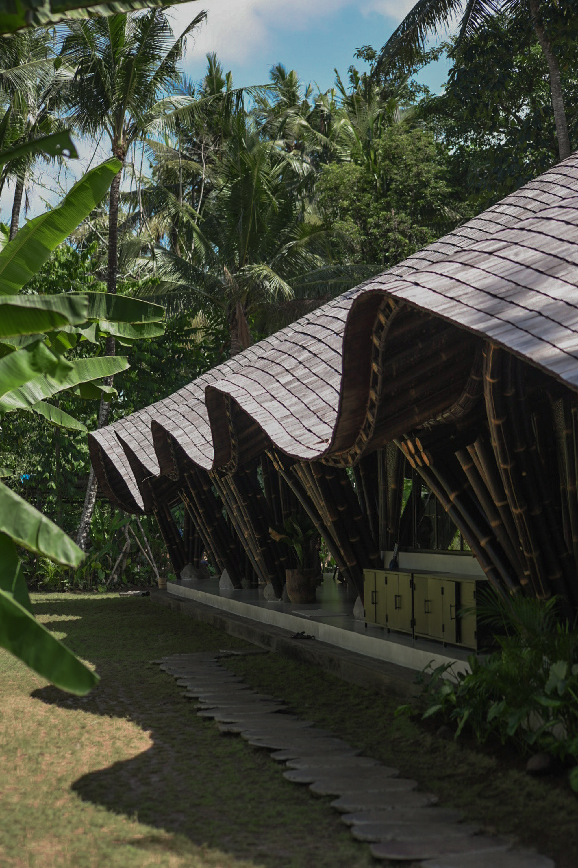 印尼度假勝地峇里島烏布 Ubud Bali 辦公室 竹構 bamboo structure Studio Lodtunduh Pablo Luna Studio 波浪狀屋簷由黑竹構築撐起，烏林木瓦片隨光影律動，延伸出通透涼爽的縱深廊道