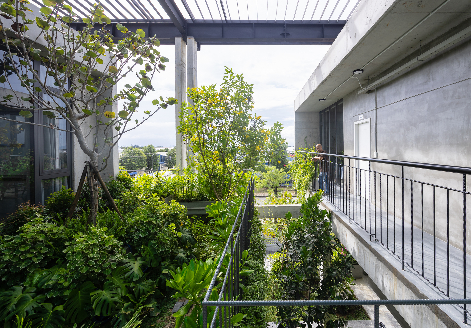 基地中央設置開放式中庭，種植本土耐旱植栽，營造自然緩衝區，並結合交叉通風與百葉窗設計，有效降低空調使用負擔