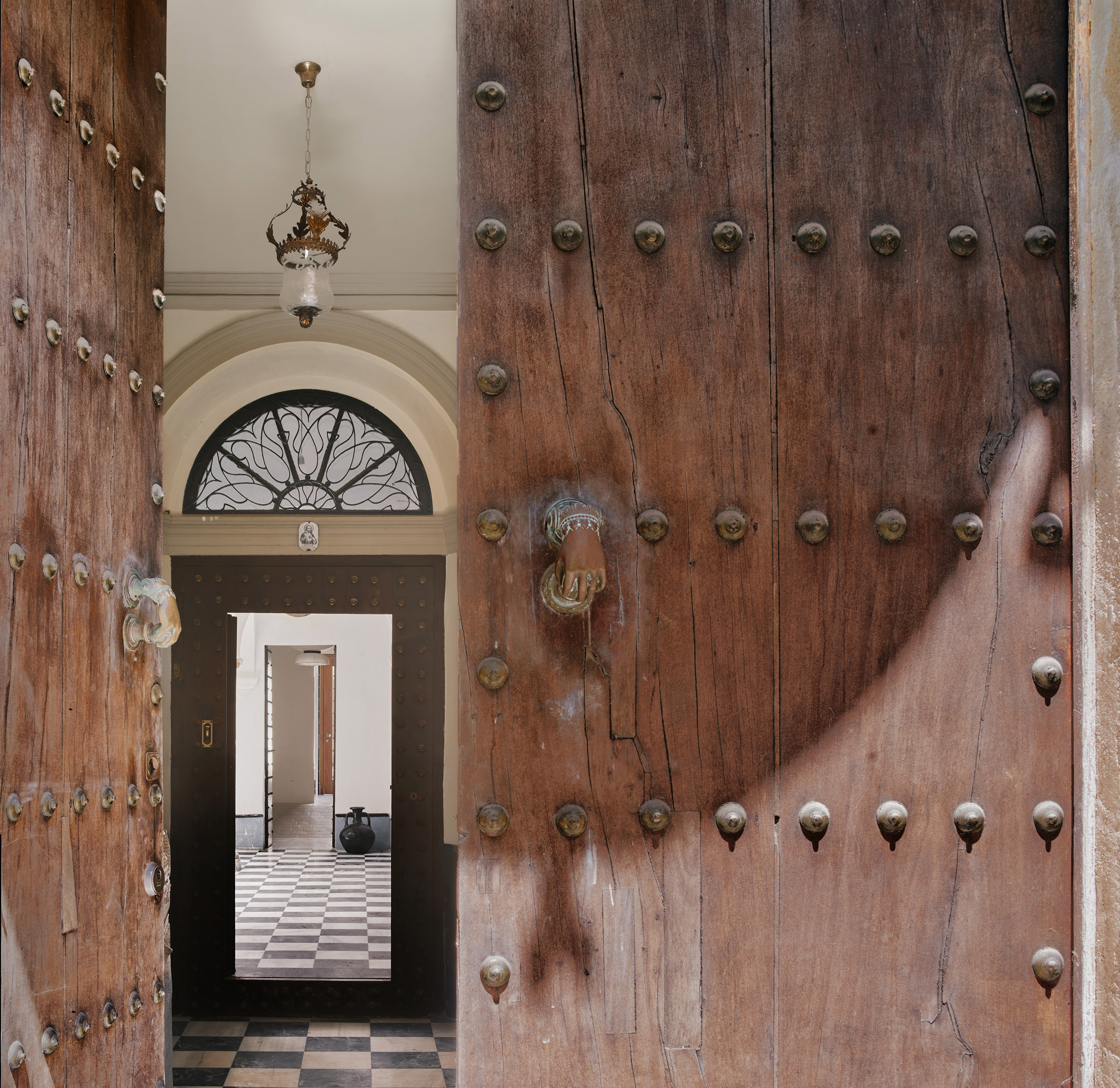 El Puerto de Santa María 住宅室內設計 Lucas y Hernández-Gil 西班牙 推開滿佈鉚釘的百年木門，獨特的掌形門環像是歷史的鑰匙。門後，黑白棋盤格地坪向內延伸，古典吊燈與弧形花窗，預告了宅邸的優雅。一道門檻，劃開了內與外，引領訪客走入一個層次豐富的時空故事