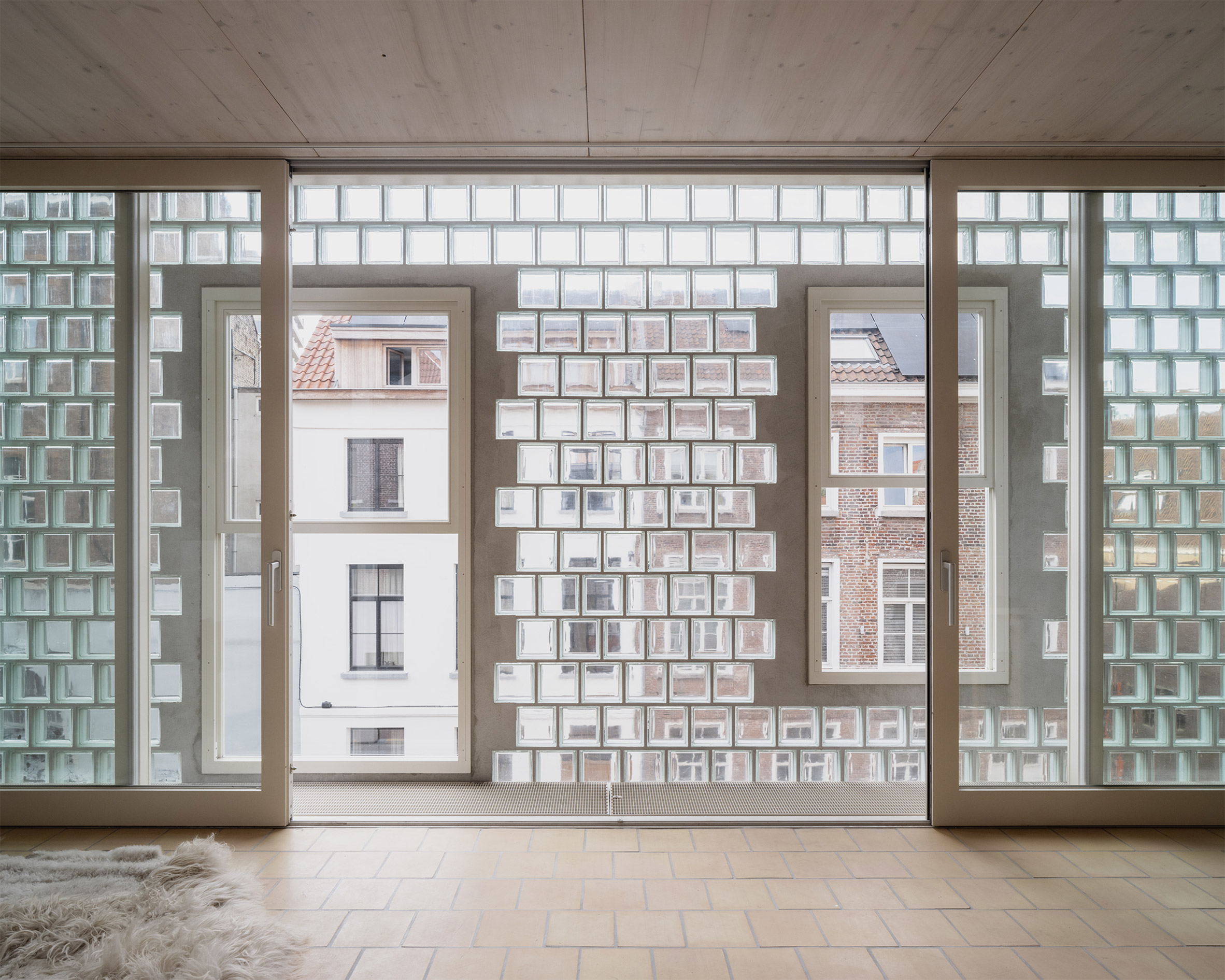 比利時 根特 Ghent 玻璃磚屋 Delmulle Delmulle Architecten Glass Brick House 立面的設計語彙其實是對典型排屋的轉譯，磚塊的鋪排模式及窗戶周圍的階梯狀混凝土框架，皆是對街角不遠處一棟建於1707年的階梯形山牆老屋的致敬