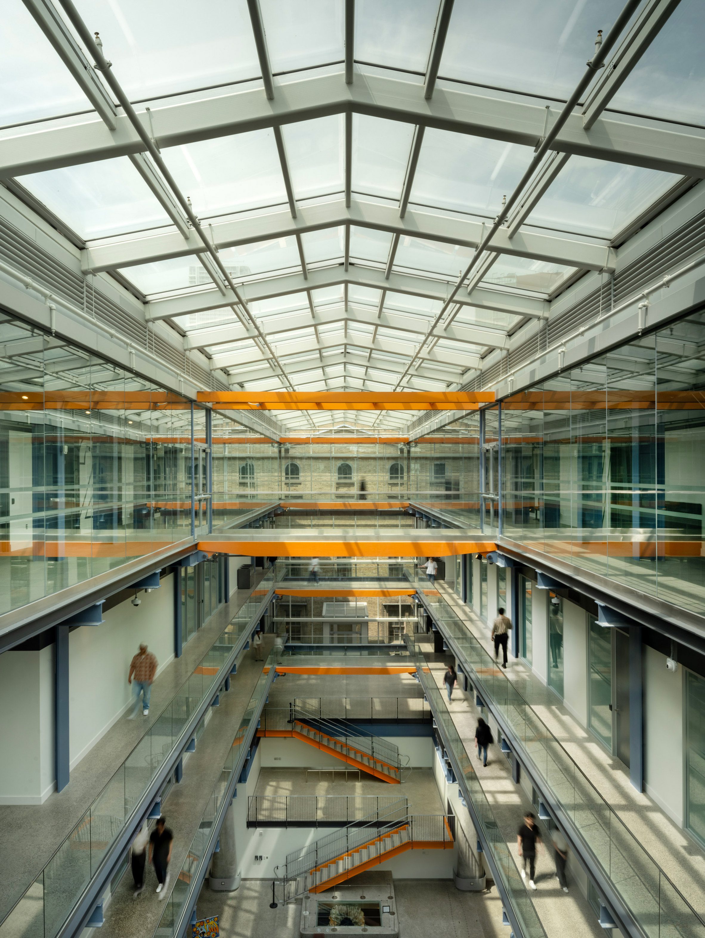 Richard Rogers RSHP 加拿大 St Lawrence Market North Toronto 貫穿建築物中央的玻璃脊柱，是整棟建築的靈魂所在。它如同一道光的瀑布，讓天光得以穿透層層樓板，直達底層的市集，使得整個中庭空間明亮而通透